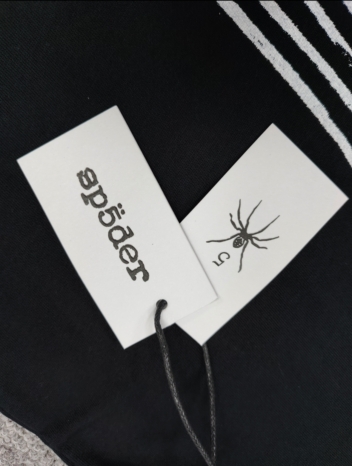 a black SP5DER Diffused Collegiate T-shirt featuring a large white, distressed graphic logo
