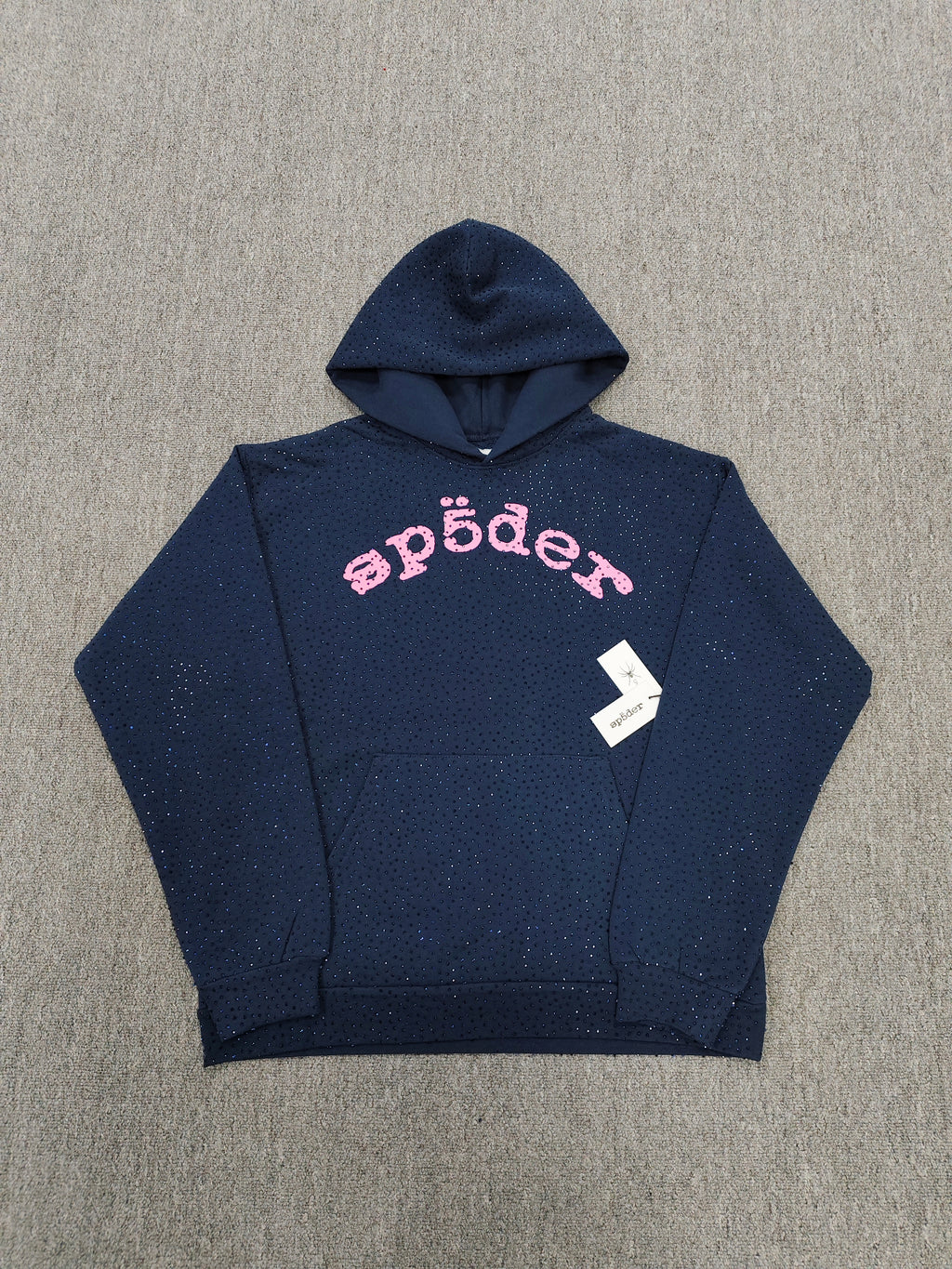 a Sp5der Worldwide navy blue hoodie featuring a pink rhinestone logo