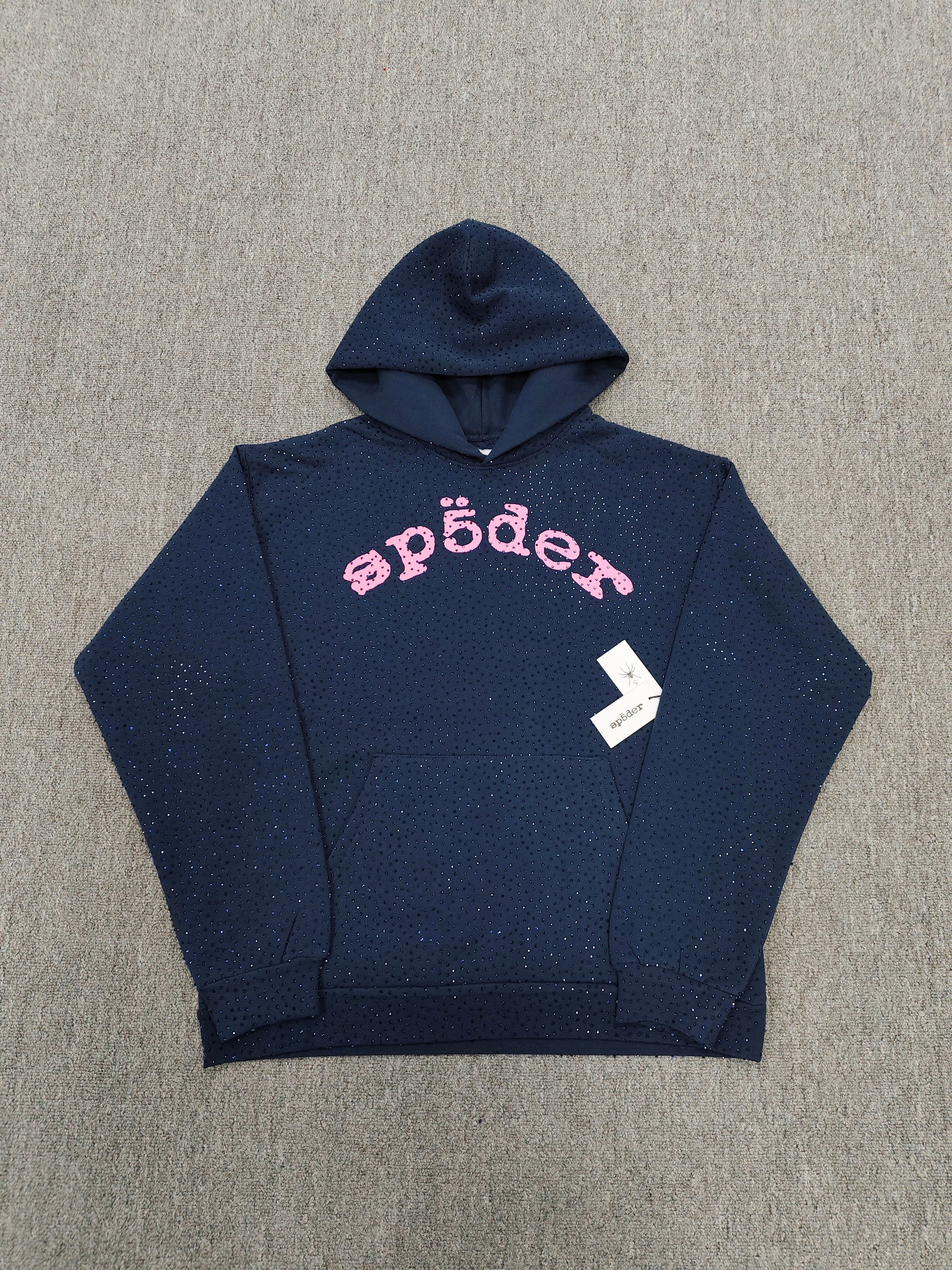 a Sp5der Worldwide navy blue hoodie featuring a pink rhinestone logo