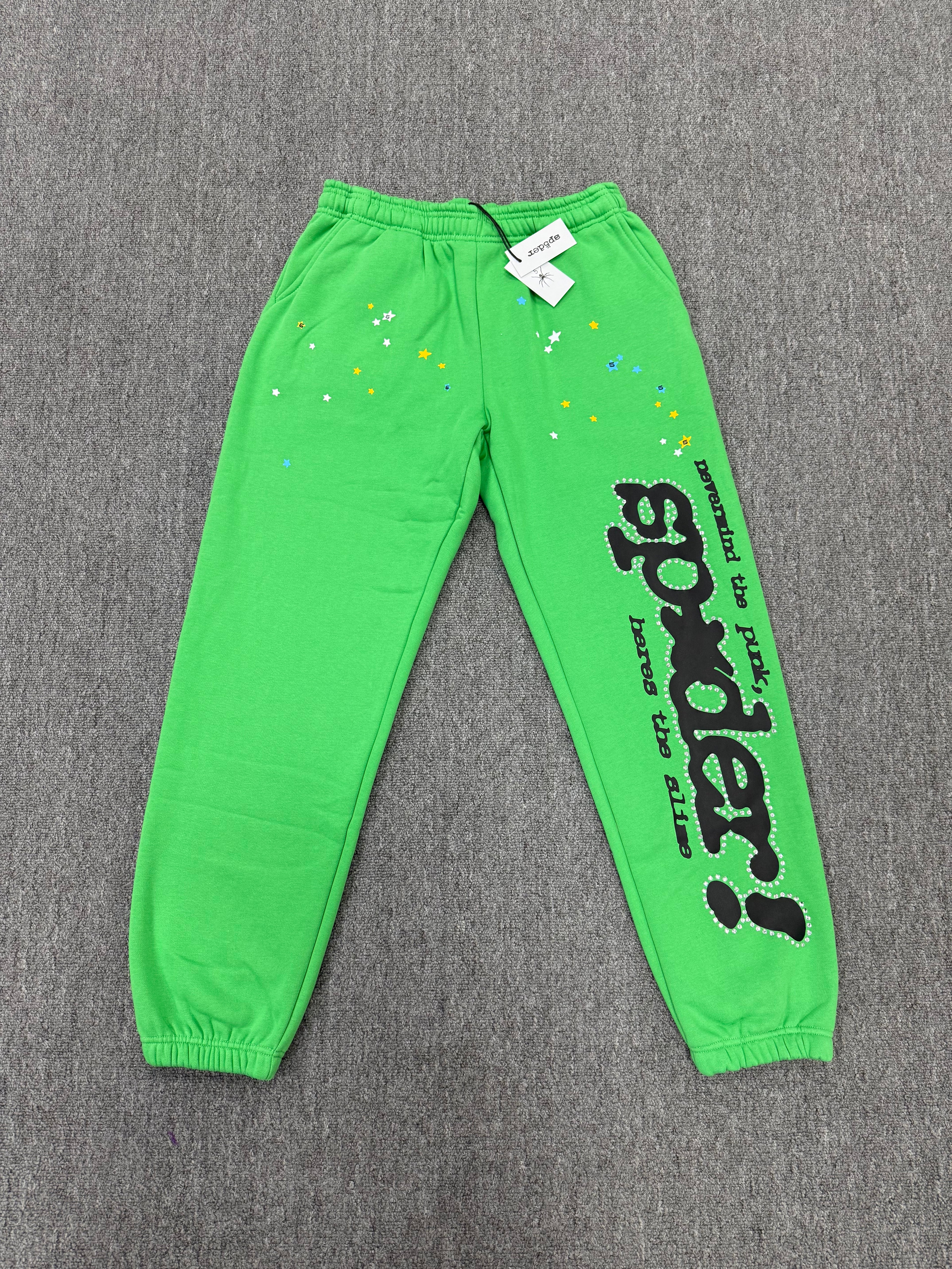 Sp5der Punk V2 Rhinestone track pants in green, featuring prominent black rhinestone-lined graphics and stars