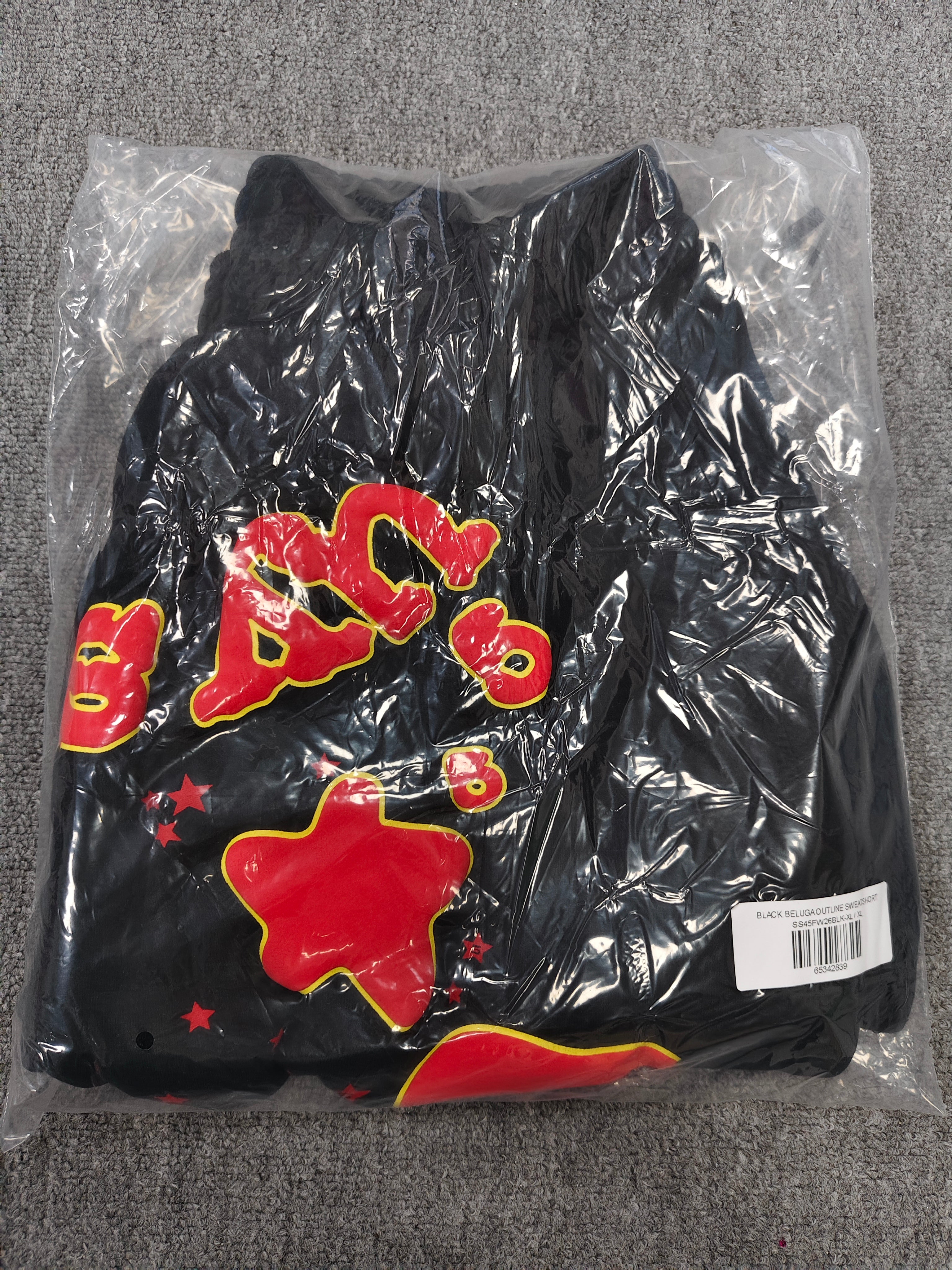 Sp5der x UY SCUTI collaboration shorts featuring bold red graphic logos on a black base