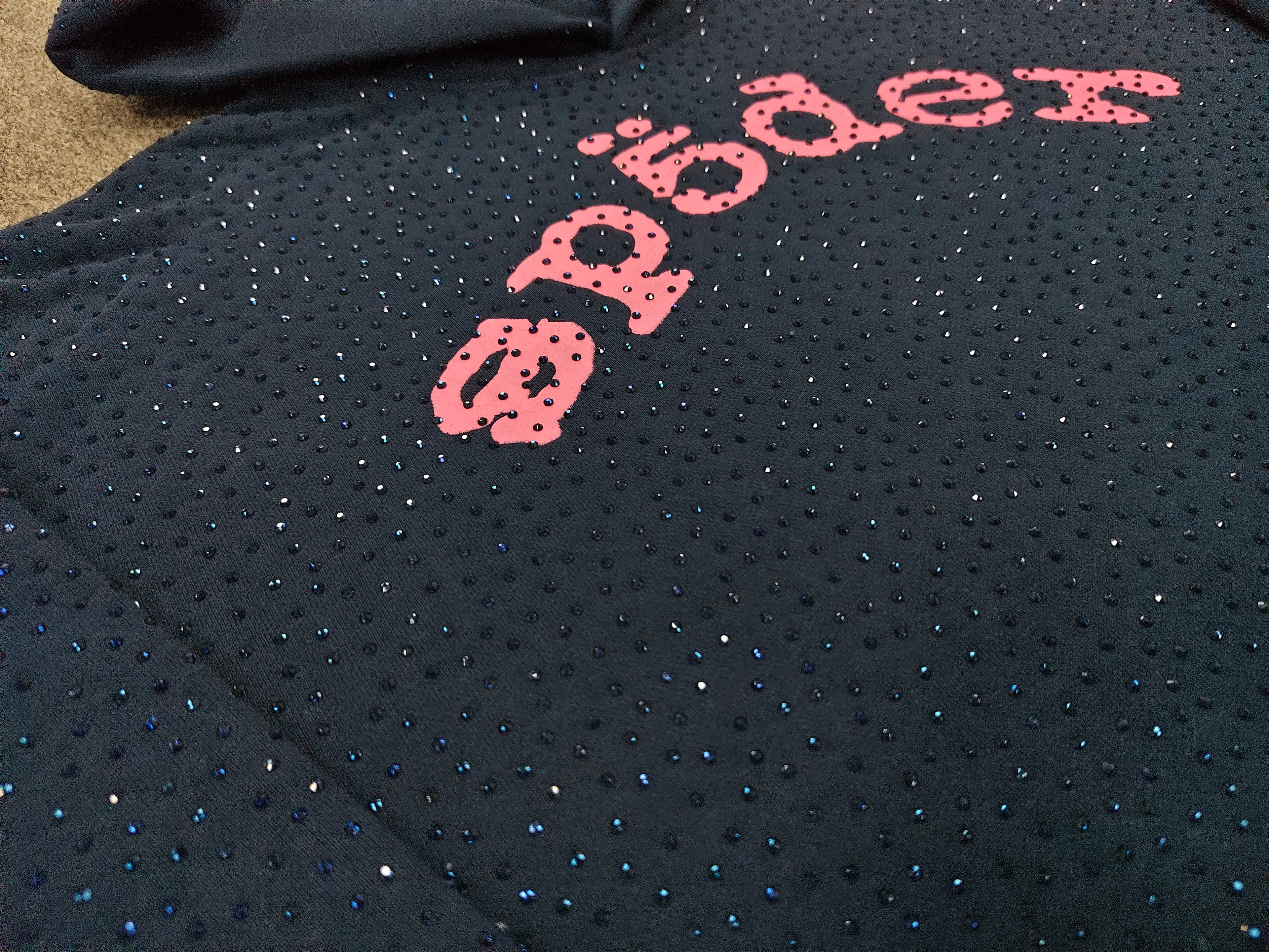 a Sp5der Worldwide navy blue hoodie featuring a pink rhinestone logo