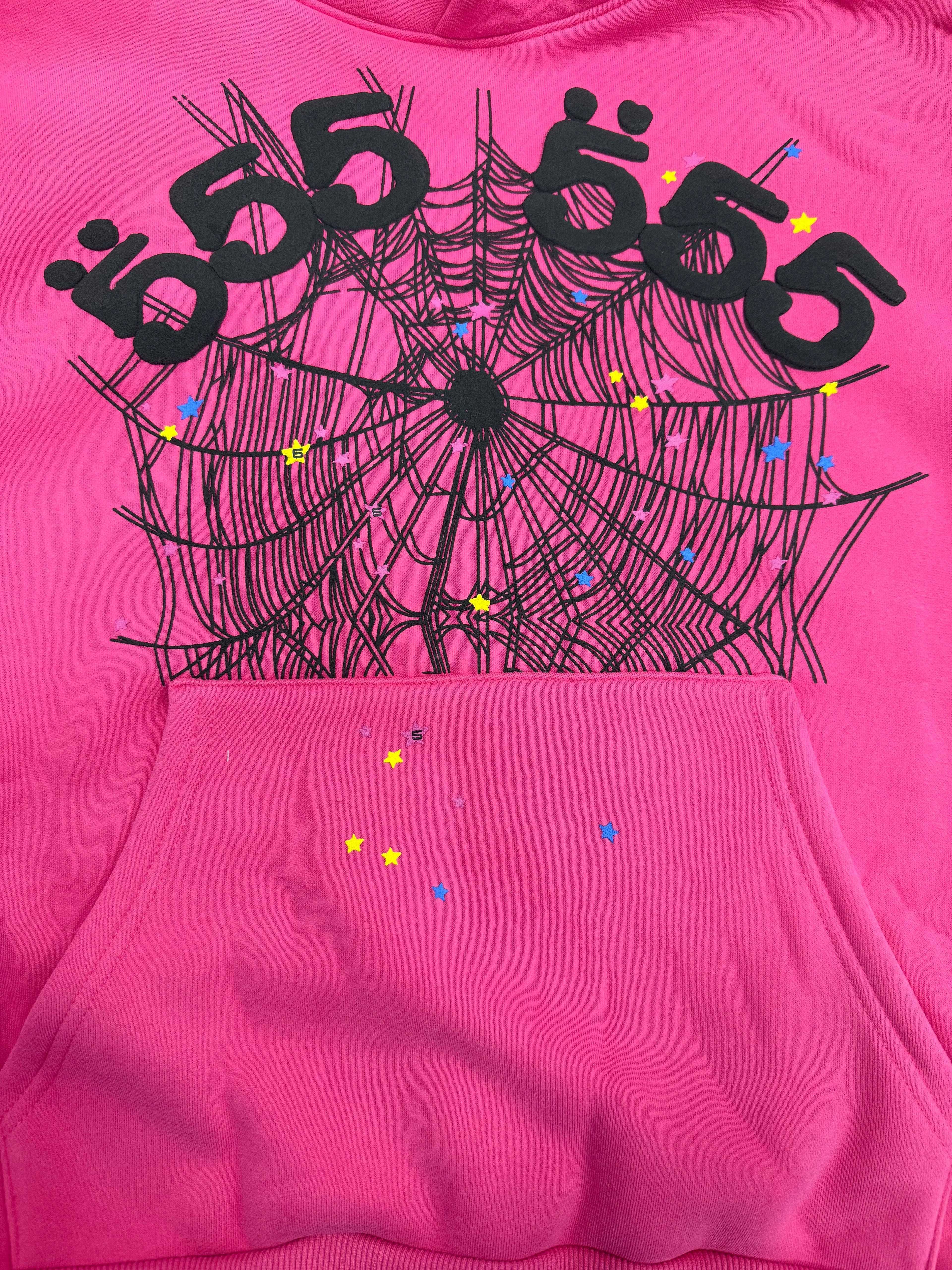 pink Sp5der graphic-print hoodie features a black spiderweb design on the front with scattered multicolored stars