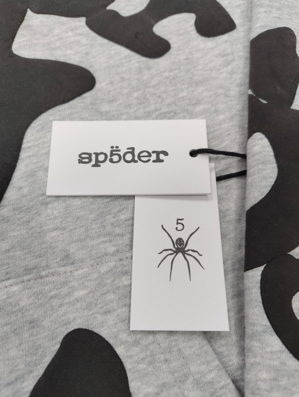 Sp5der Worldwide Beluga hoodie features a distinctive black star graphic across the chest on a light grey heather fabric