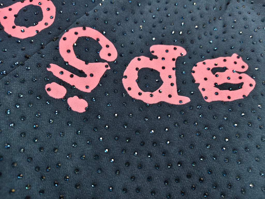 Sp5der jogger shorts are a navy blue color with a pink text graphic and rhinestone details
