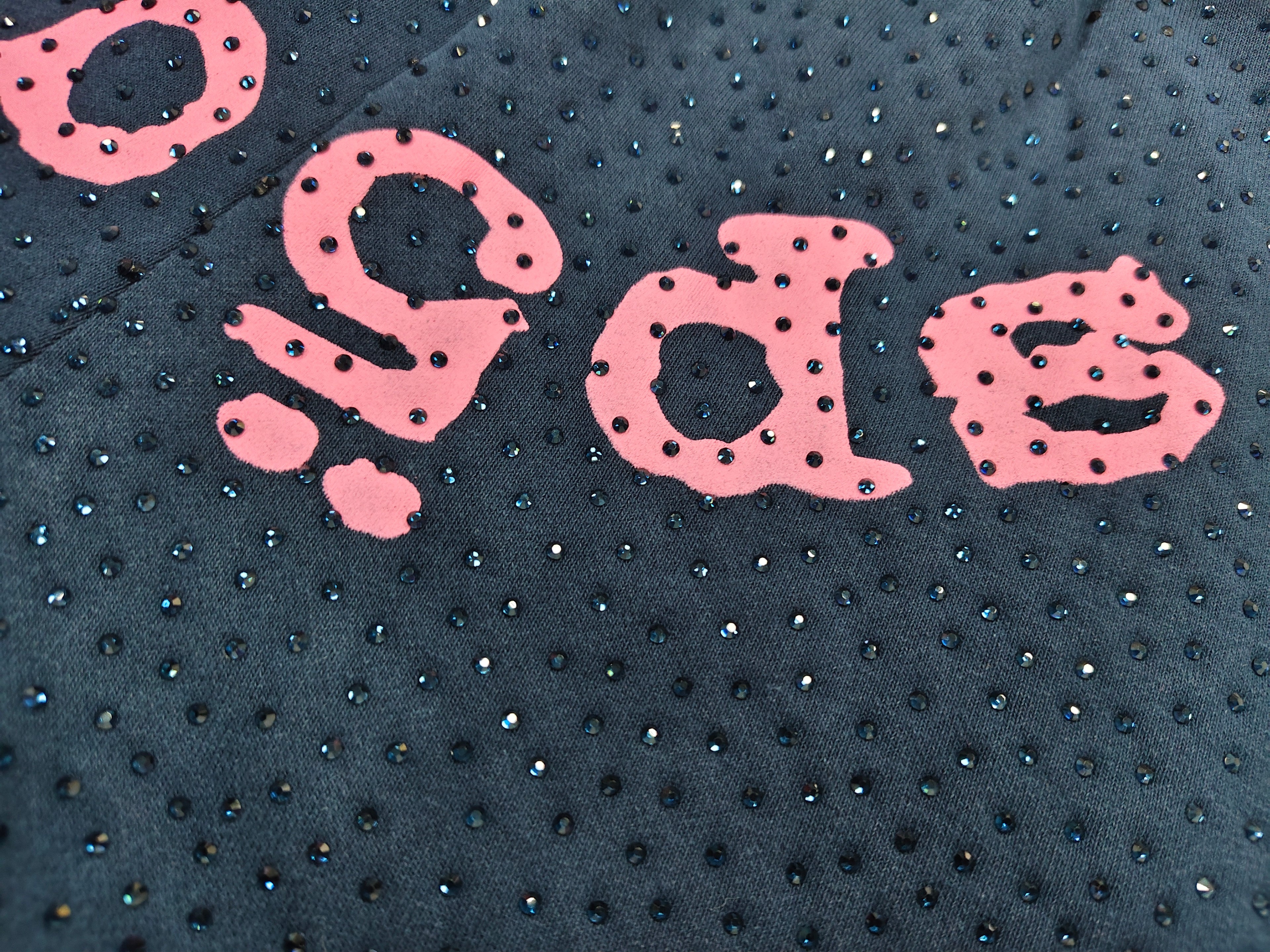 Sp5der jogger shorts are a navy blue color with a pink text graphic and rhinestone details