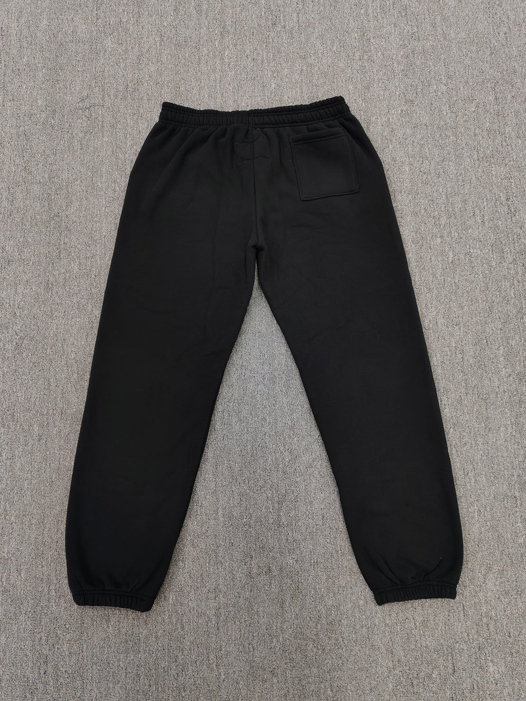 black Sp5der x Coulda Been sweatpants featuring a prominent pink "spider!" graphic and multi-colored star embroidery