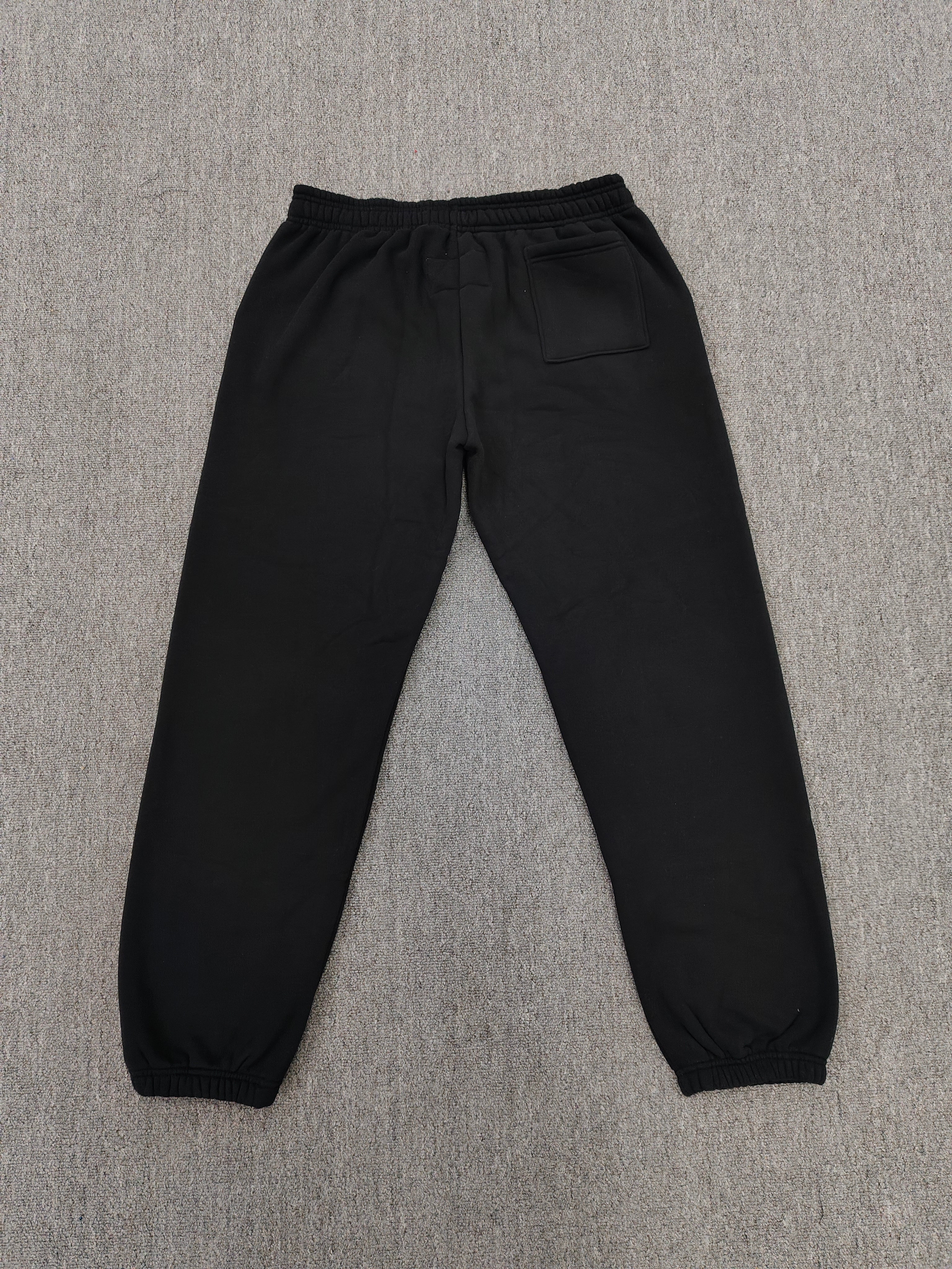 black Sp5der x Coulda Been sweatpants featuring a prominent pink "spider!" graphic and multi-colored star embroidery
