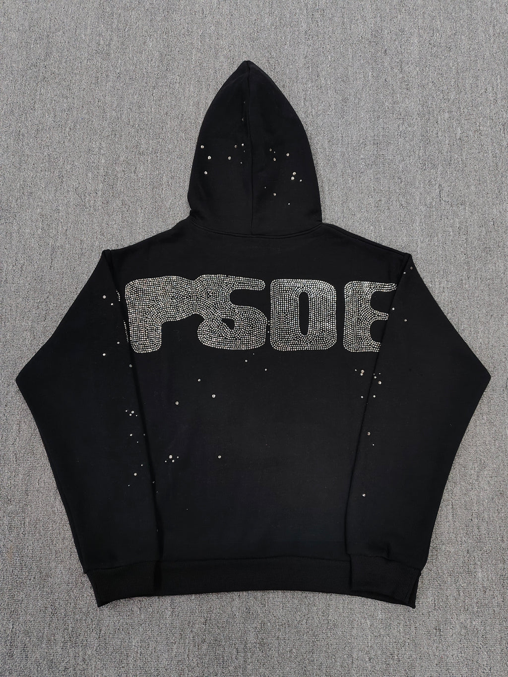 a Sp5der Rhinestone Silk Hoodie in black, featuring a prominent rhinestone web graphic on the front