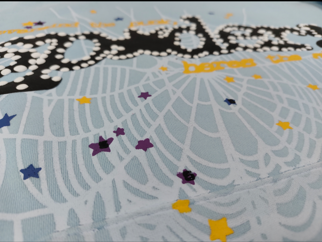 a light blue Sp5der Worldwide hoodie featuring a prominent black graphic logo and a white spiderweb design filled with colorful stars