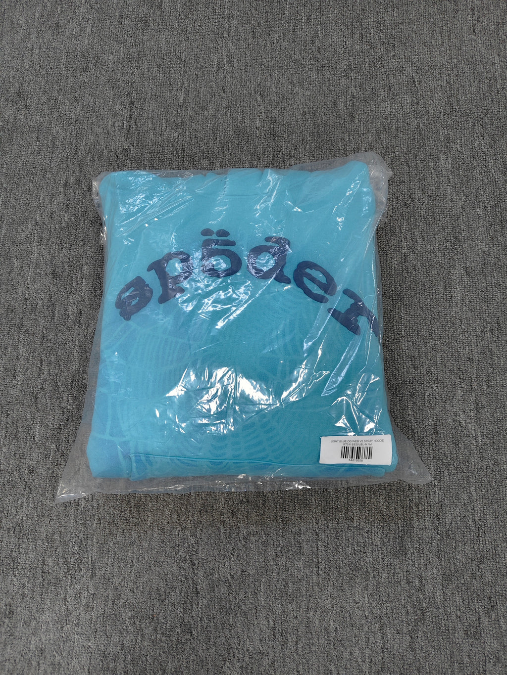 light blue Sp5der OG Web V2 Spray Hoodie features a prominent, sprayed-on navy spiderweb graphic