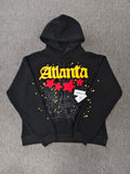 black SP5DER Atlanta hoodie features yellow lettering, red stars, and a spiderweb graphic