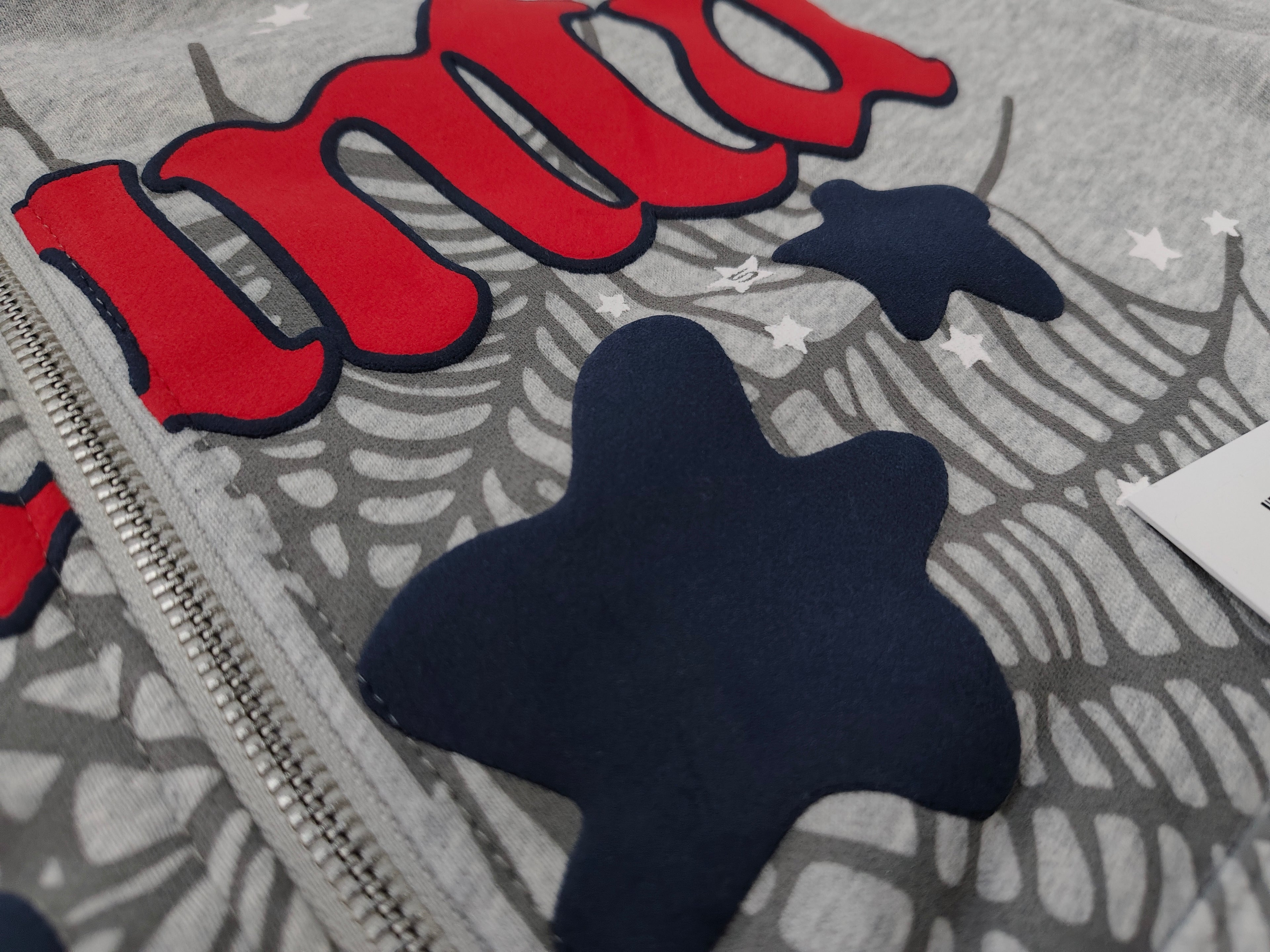 Sp5der Atlanta Full Zip Hoodie in Heather Grey, featuring a red "Atlanta" logo graphic with navy blue star accents