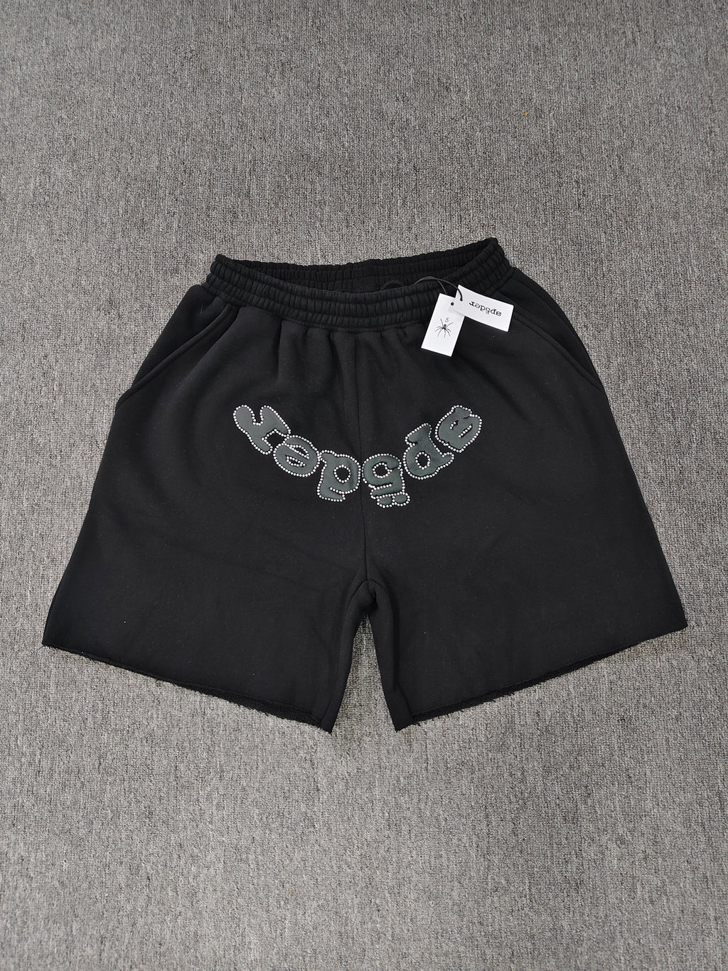 black Sp5der shorts feature a rhinestone-embellished logo and a spider web graphic