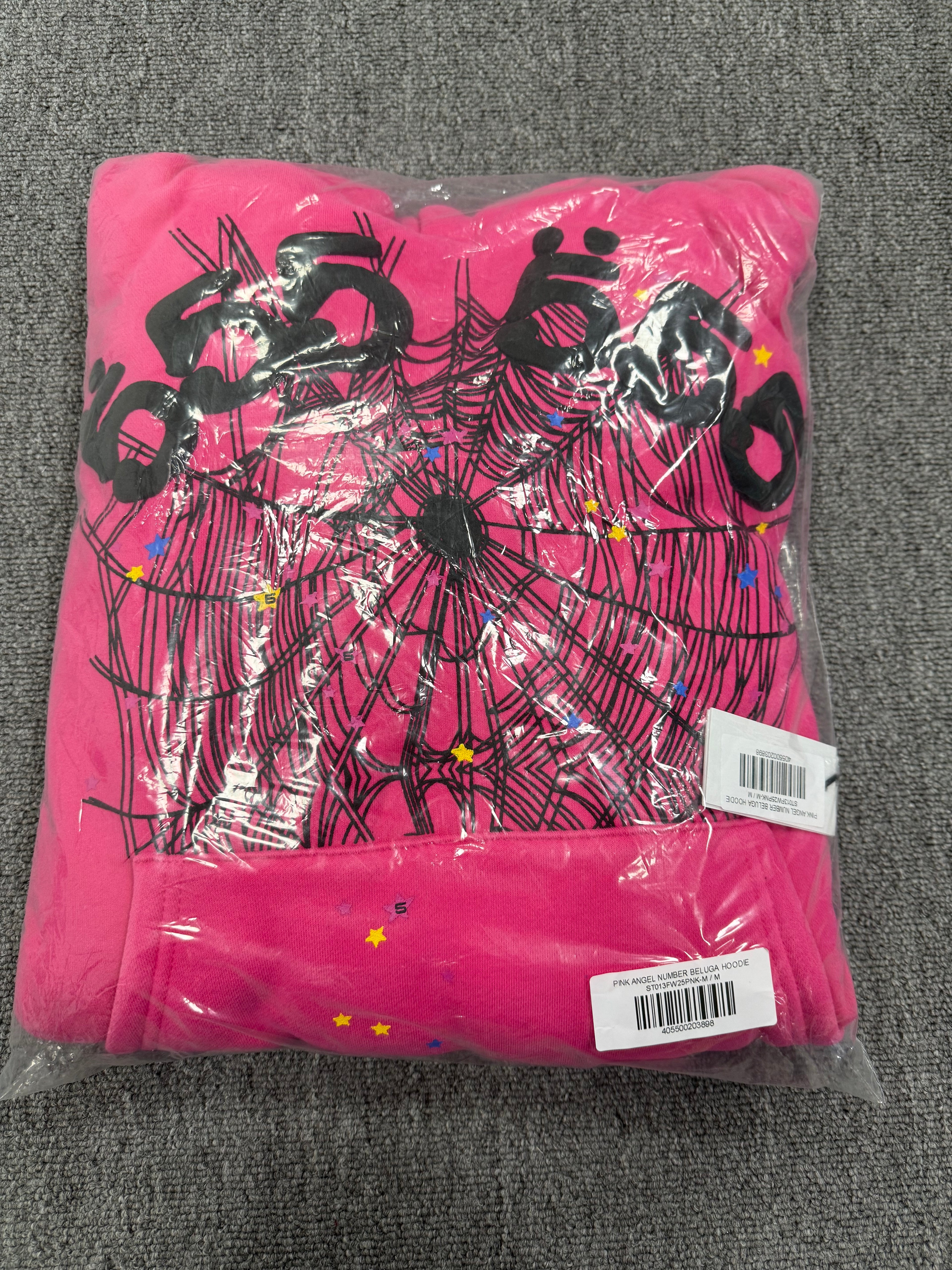 pink Sp5der graphic-print hoodie features a black spiderweb design on the front with scattered multicolored stars