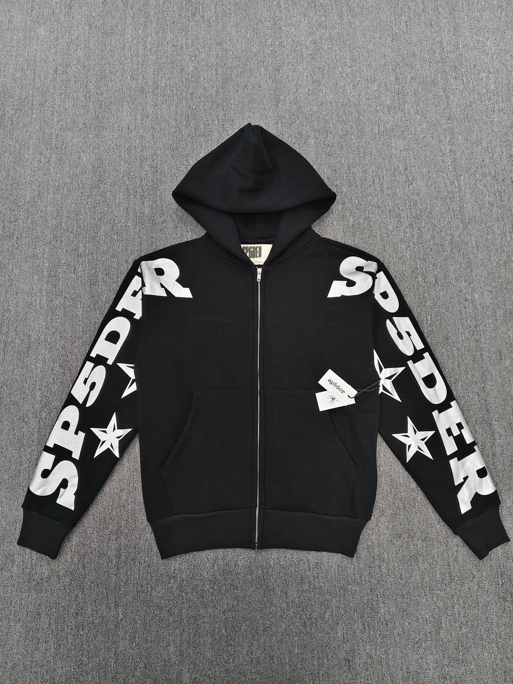 a Sp5der MX555 Zip Hoodie in black, featuring white graphic lettering and star prints on the sleeves