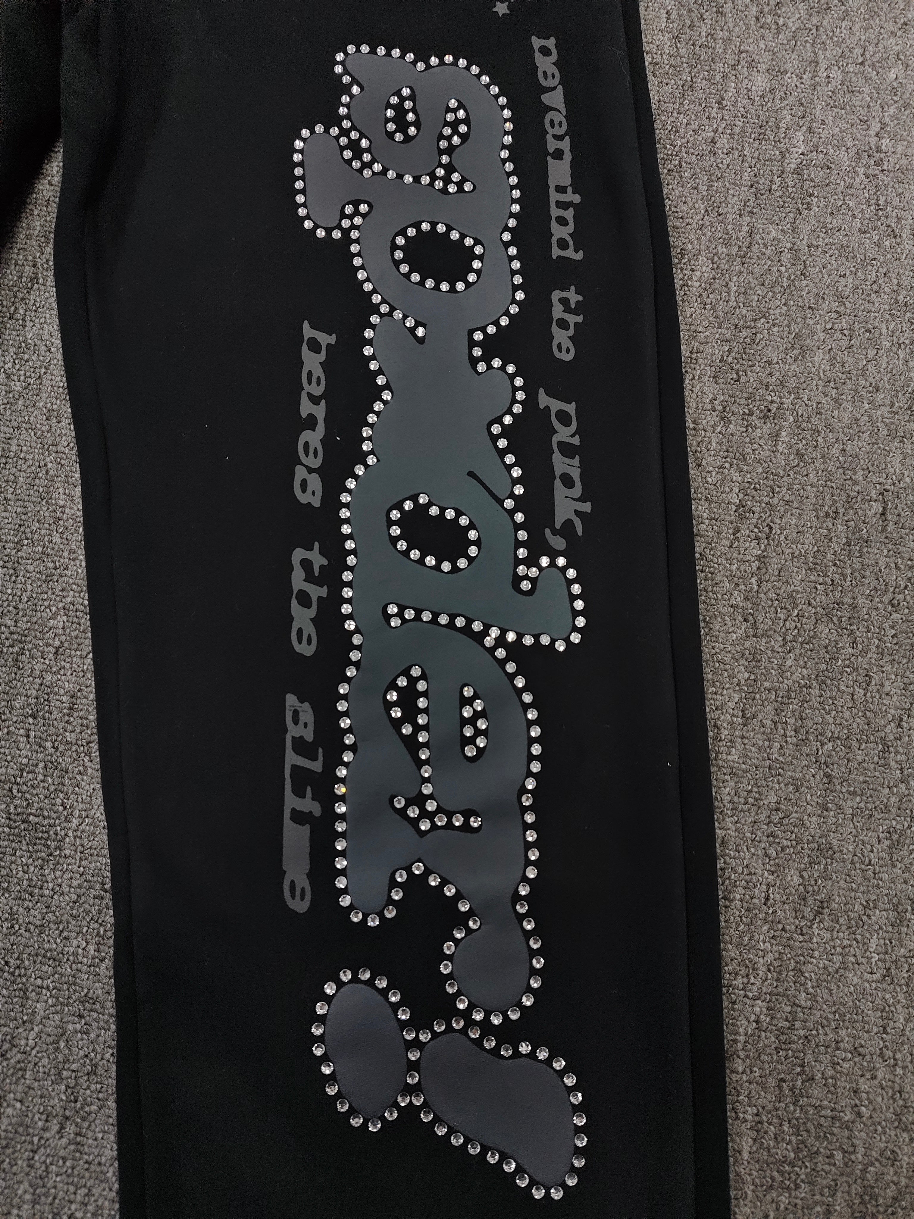 black SP5DER Rhinestone Punk V2 track pants feature rhinestone star embellishments and a rhinestone-encrusted logo