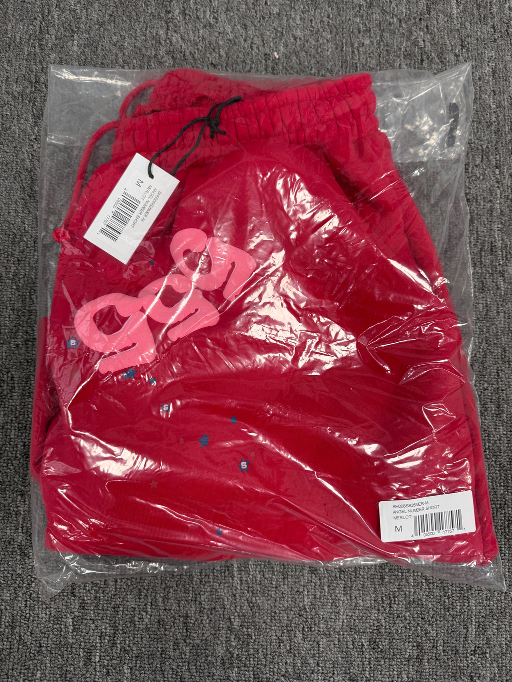 red Sp5der Angel Number Shorts featuring pink "555" graphics and star-shaped paint splatters