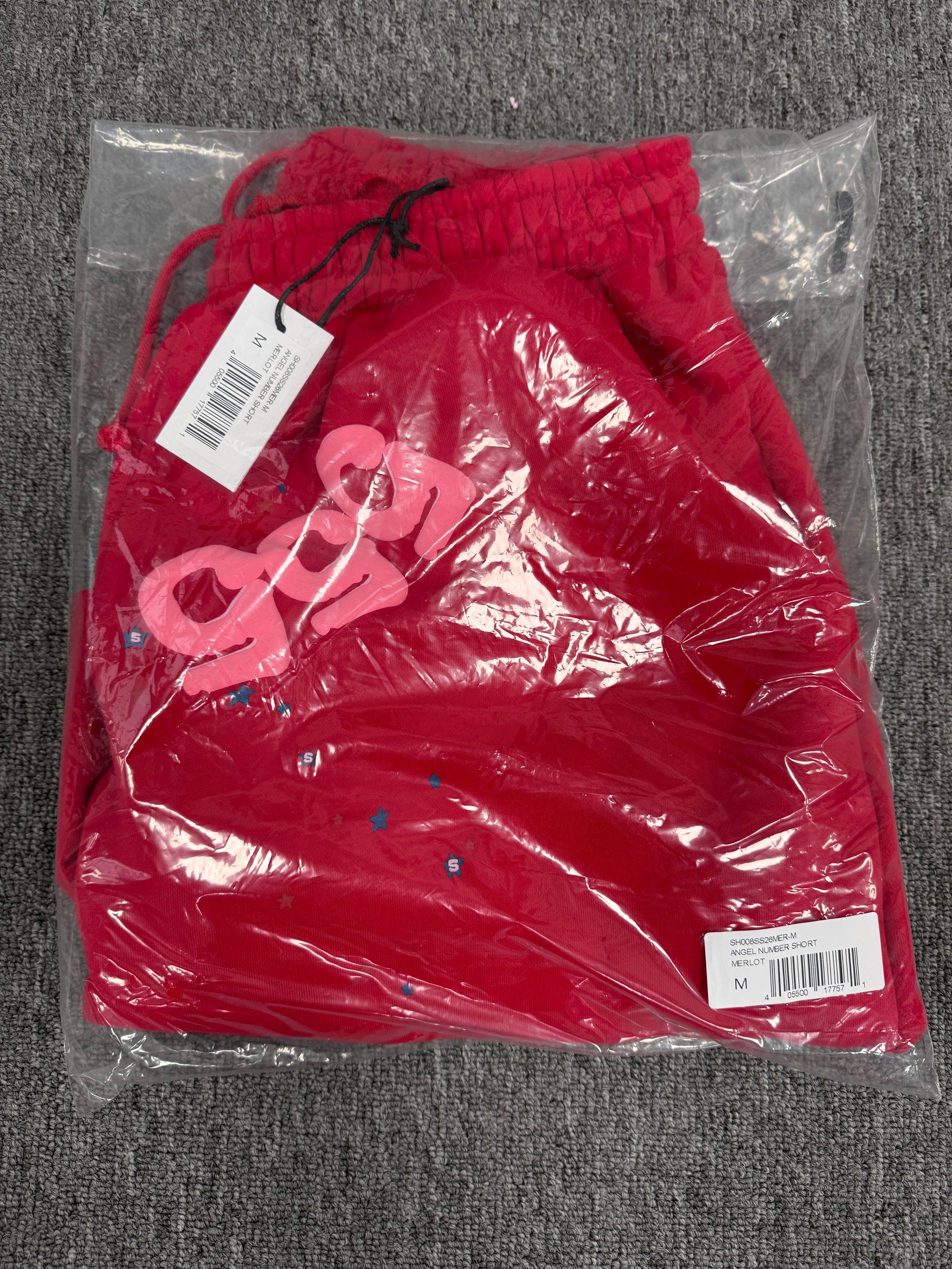 red Sp5der Angel Number Shorts featuring pink "555" graphics and star-shaped paint splatters