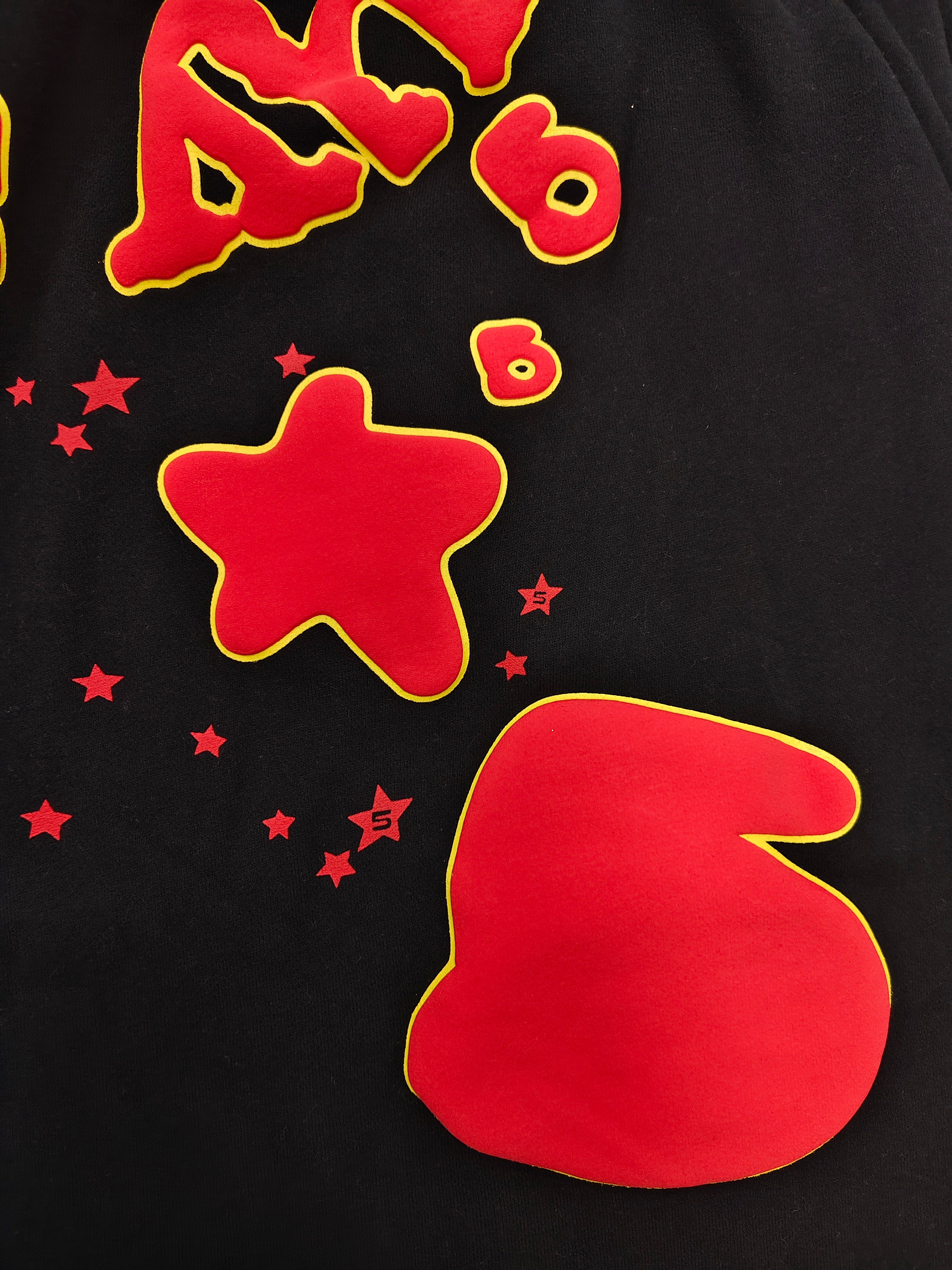 Sp5der x UY SCUTI collaboration shorts featuring bold red graphic logos on a black base