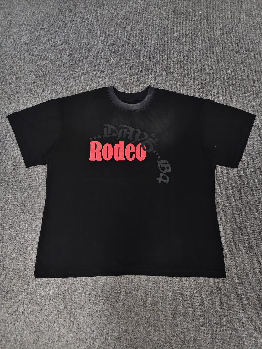a black Travis Scott x Sp5der "Days Before Rodeo" collaboration t-shirt featuring a distinctive red "Rodeo" graphic and faded branding