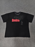 a black Travis Scott x Sp5der "Days Before Rodeo" collaboration t-shirt featuring a distinctive red "Rodeo" graphic and faded branding