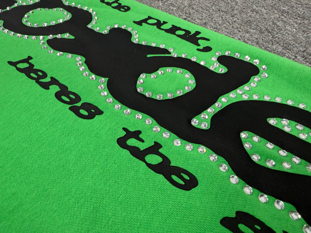 Sp5der Punk V2 Rhinestone track pants in green, featuring prominent black rhinestone-lined graphics and stars