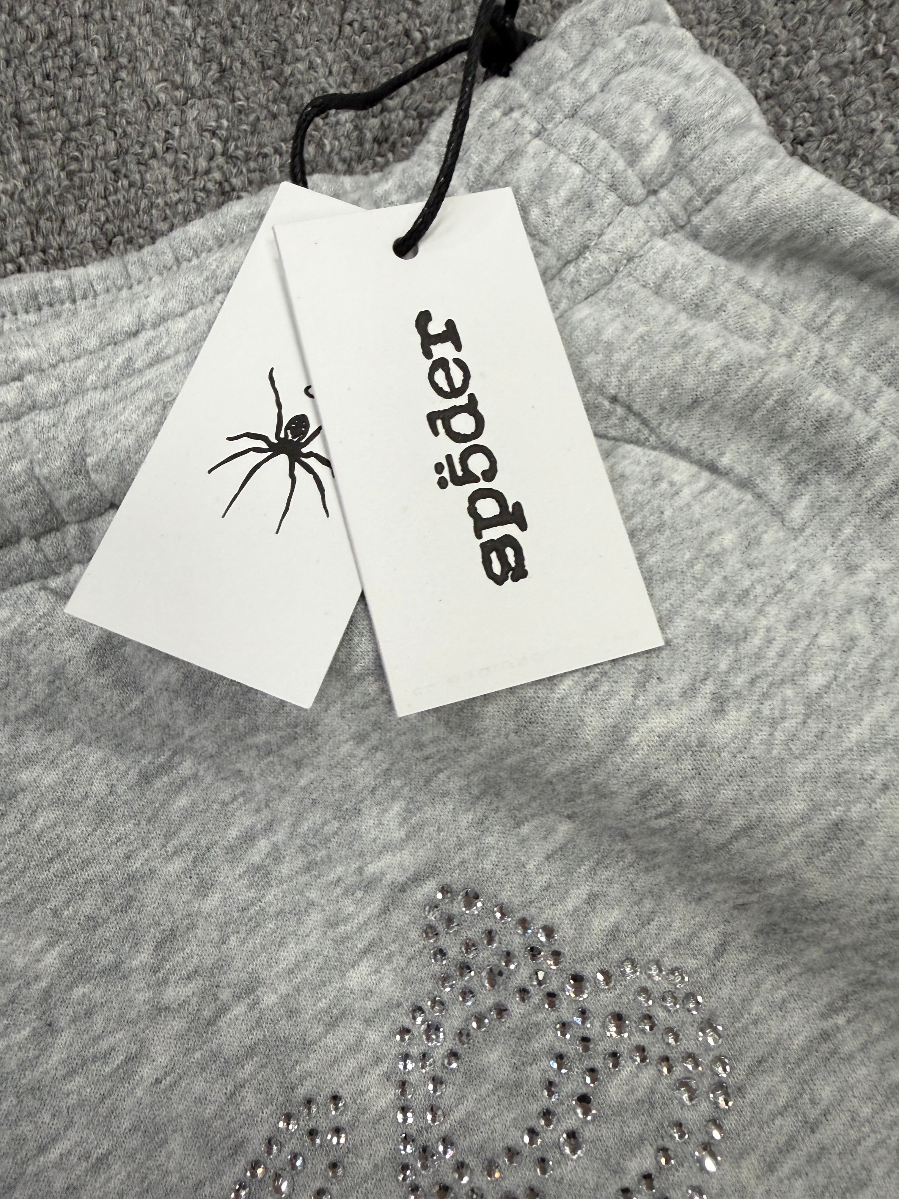 light grey sp5der joggers feature a unique rhinestone across the front hip area