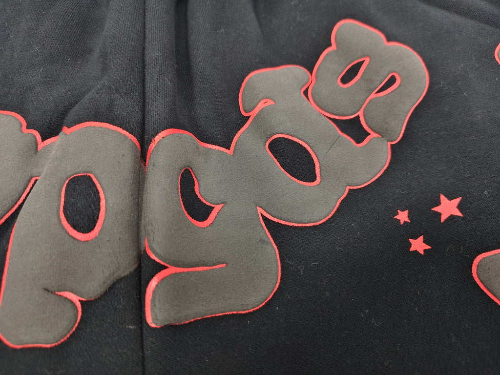 Sp5der Beluga Outline Sweatshorts in black, featuring prominent red-outlined graphic logos and stars