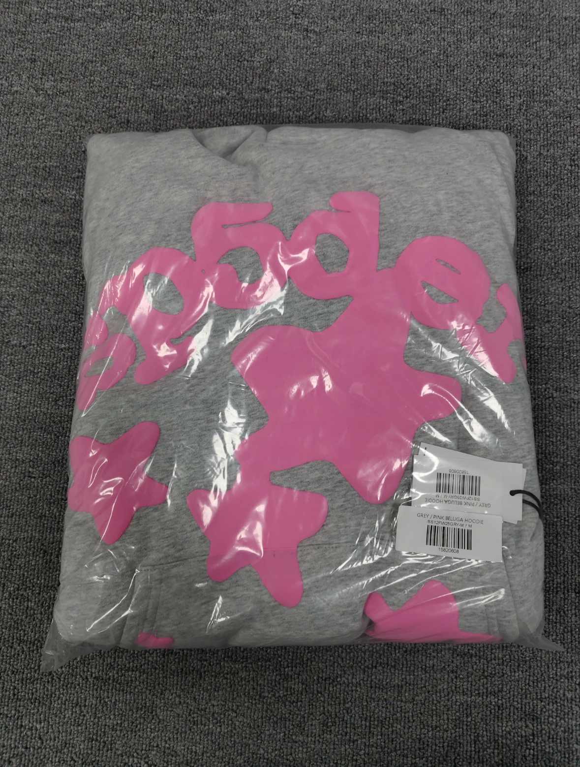 a grey Sp5der "Beluga" hoodie featuring pink star graphics and brand lettering