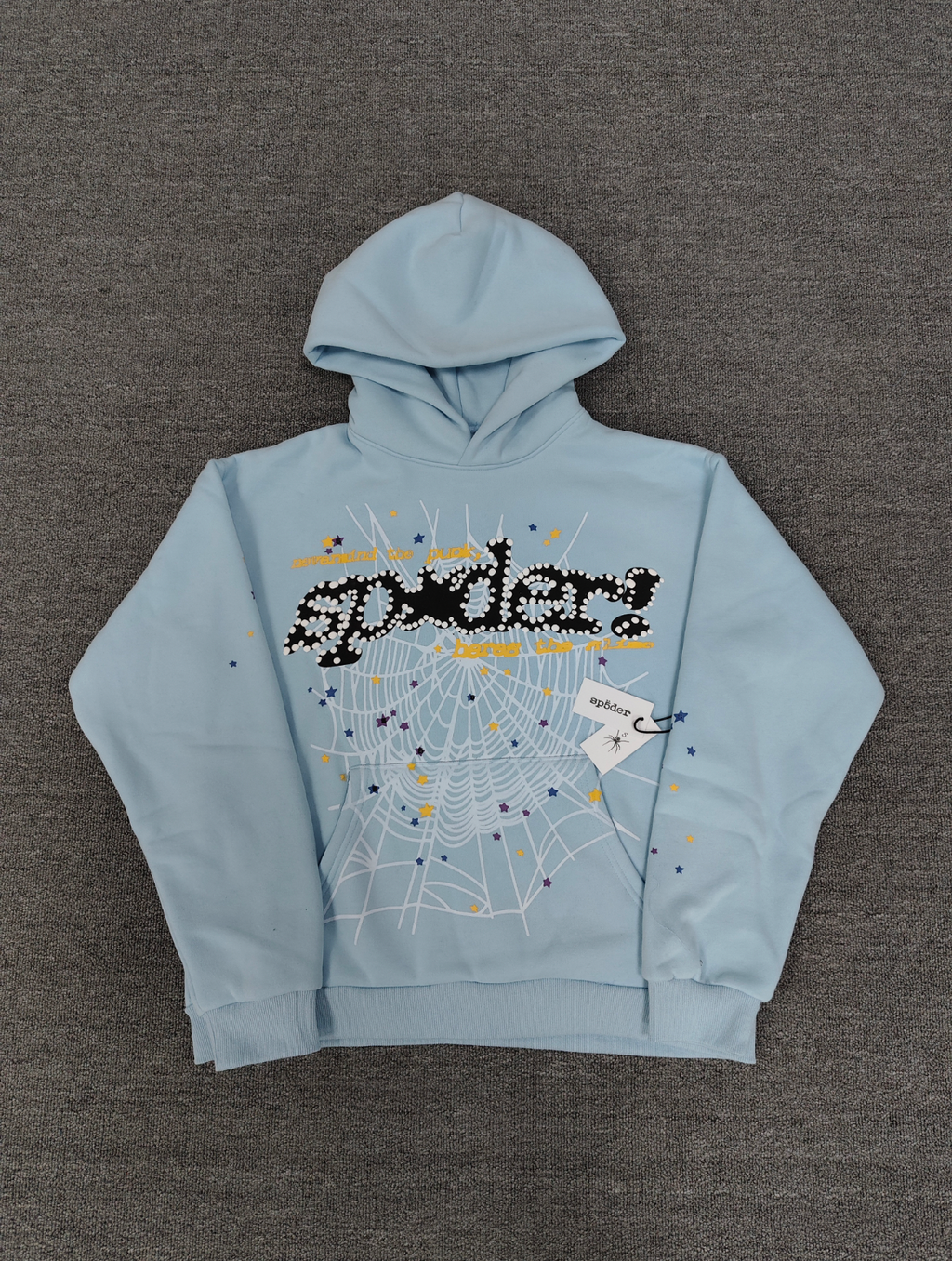 a light blue Sp5der Worldwide hoodie featuring a prominent black graphic logo and a white spiderweb design filled with colorful stars