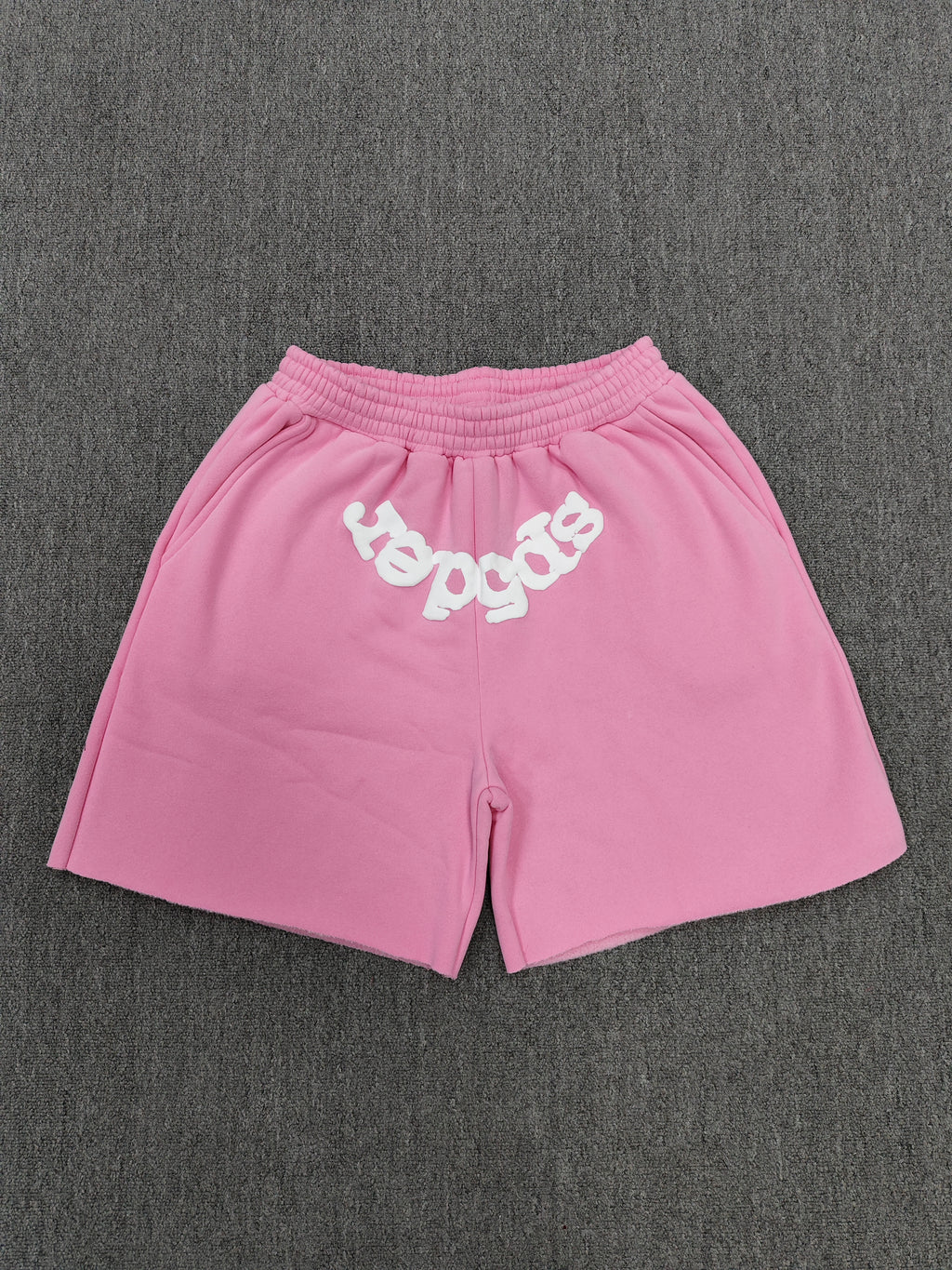 pink Sp5der jogger shorts feature a prominent white "sp5der" bubble letter graphic across the front