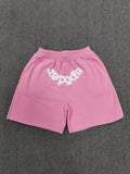 pink Sp5der jogger shorts feature a prominent white "sp5der" bubble letter graphic across the front
