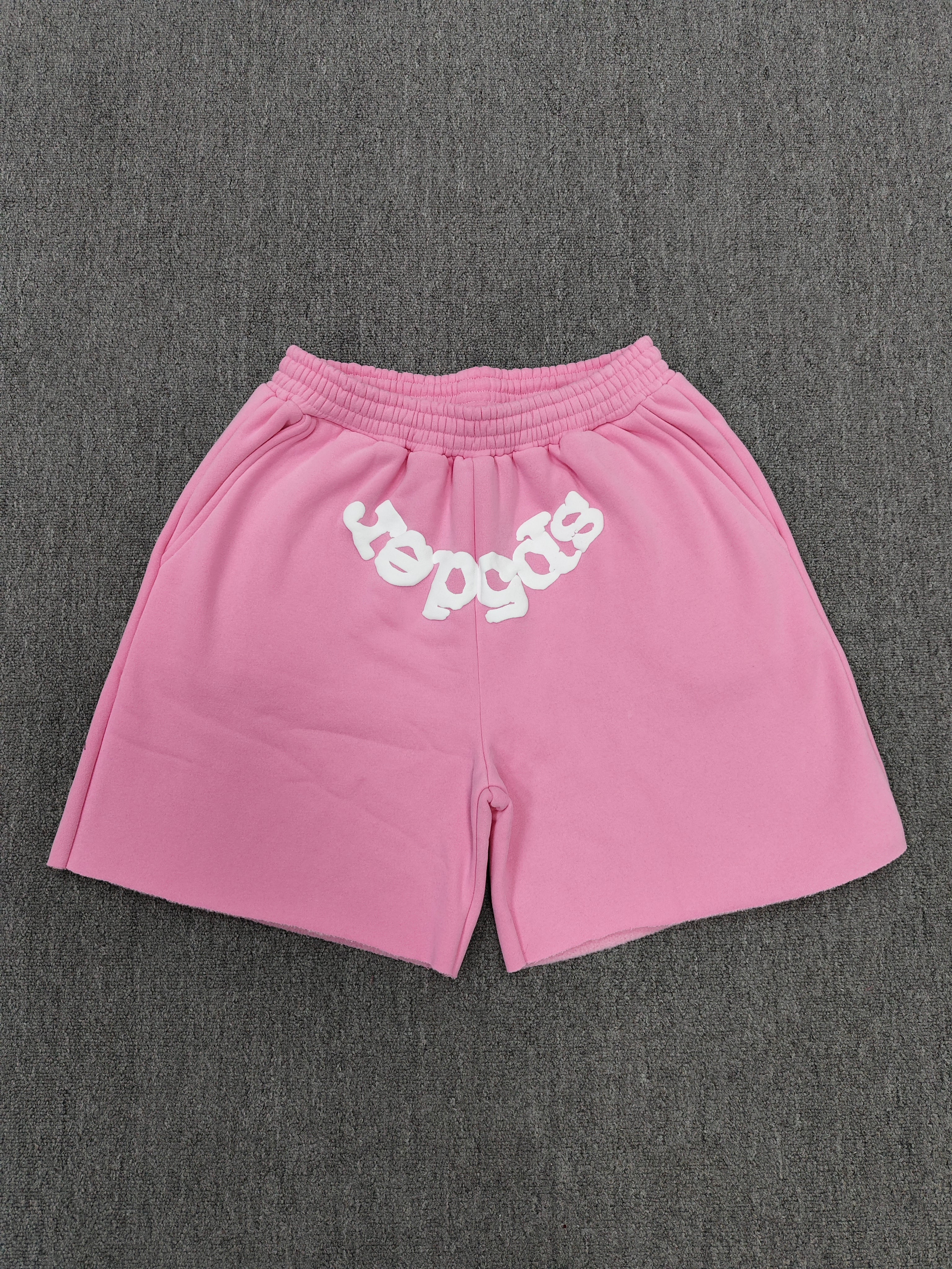 pink Sp5der jogger shorts feature a prominent white "sp5der" bubble letter graphic across the front