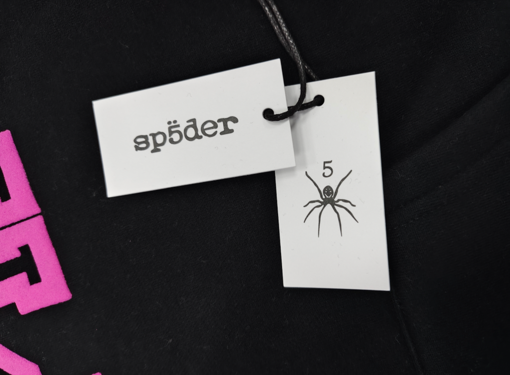 a black Sp5der Arachnophobia hoodie with vibrant pink lettering