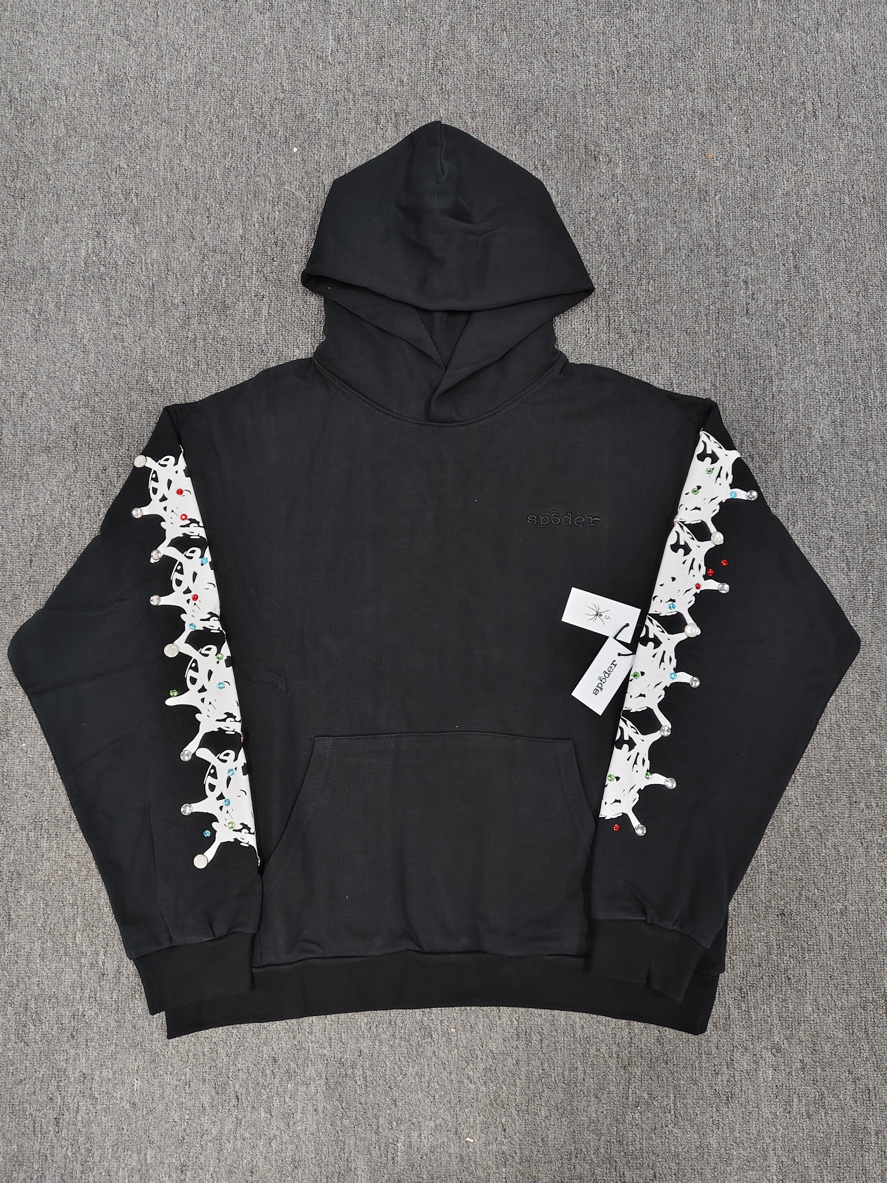 a black Sp5der Stone Hoodie featuring rhinestone embellishments along the sleeves