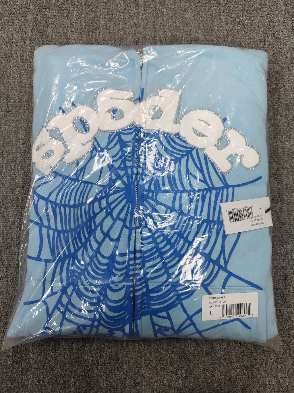 Sp5der OG Web Zip Up hoodie in Sky Blue features a prominent 3D puff-printed spider web graphic and rhinestone embellishments