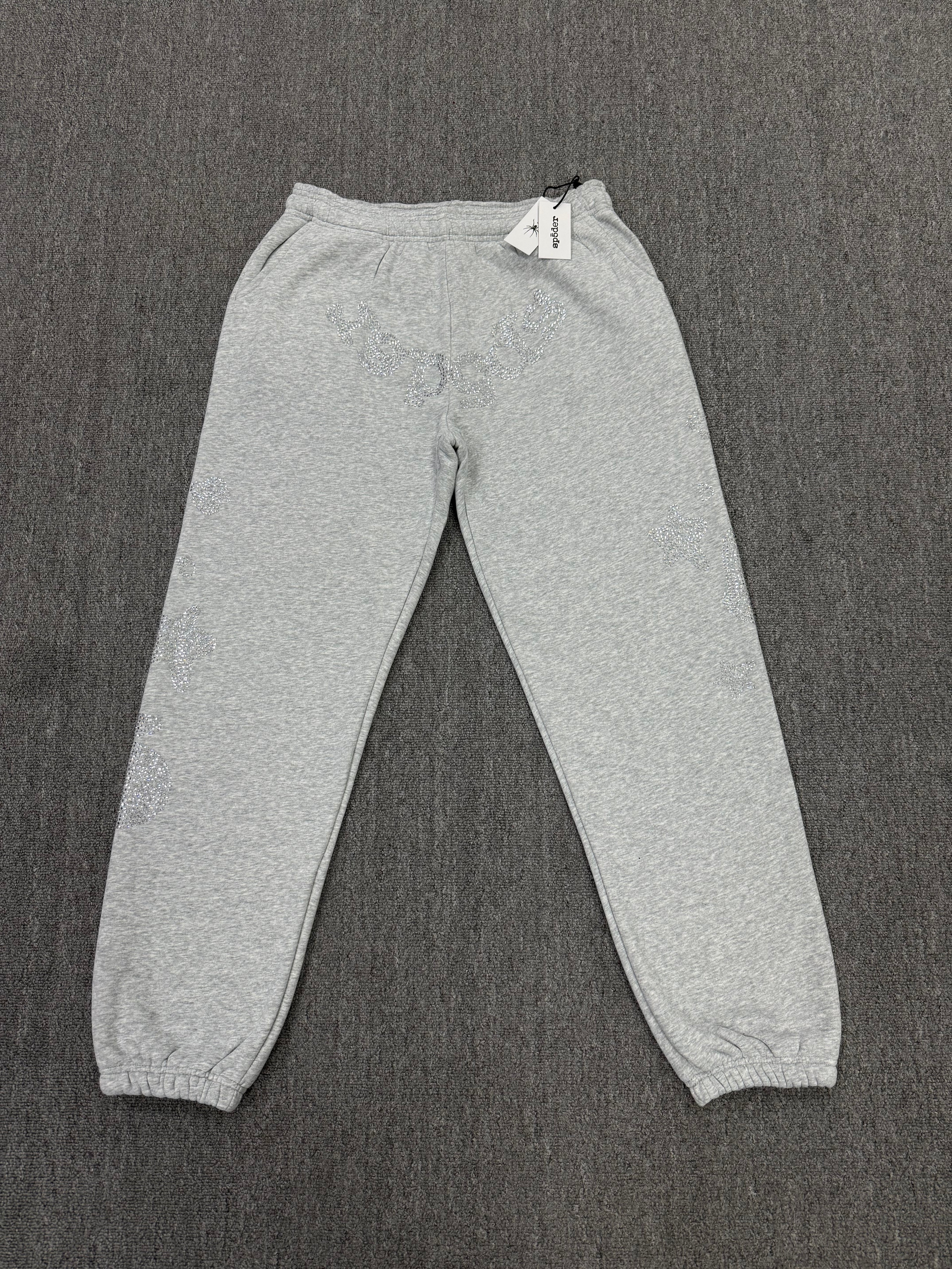 light grey sp5der joggers feature a unique rhinestone across the front hip area