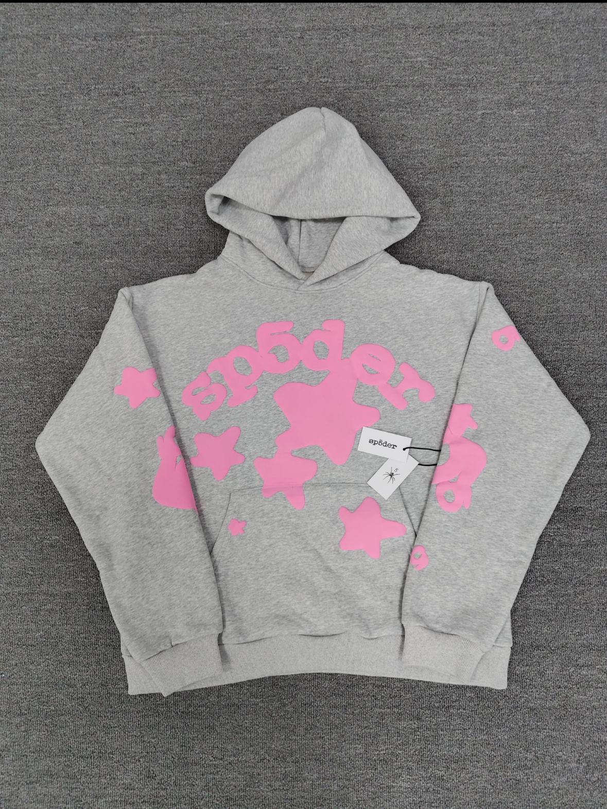 a grey Sp5der "Beluga" hoodie featuring pink star graphics and brand lettering