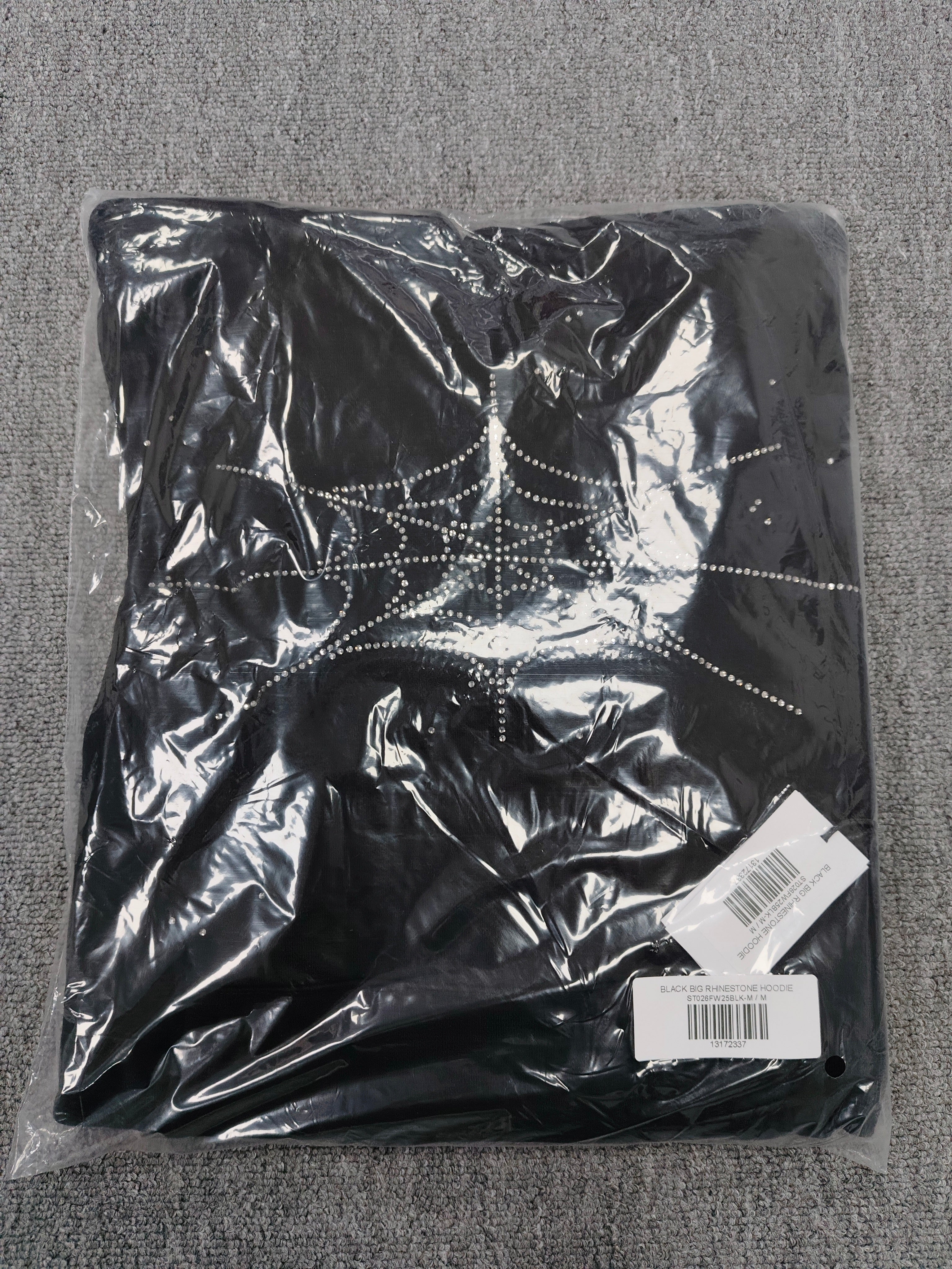 a Sp5der Rhinestone Silk Hoodie in black, featuring a prominent rhinestone web graphic on the front