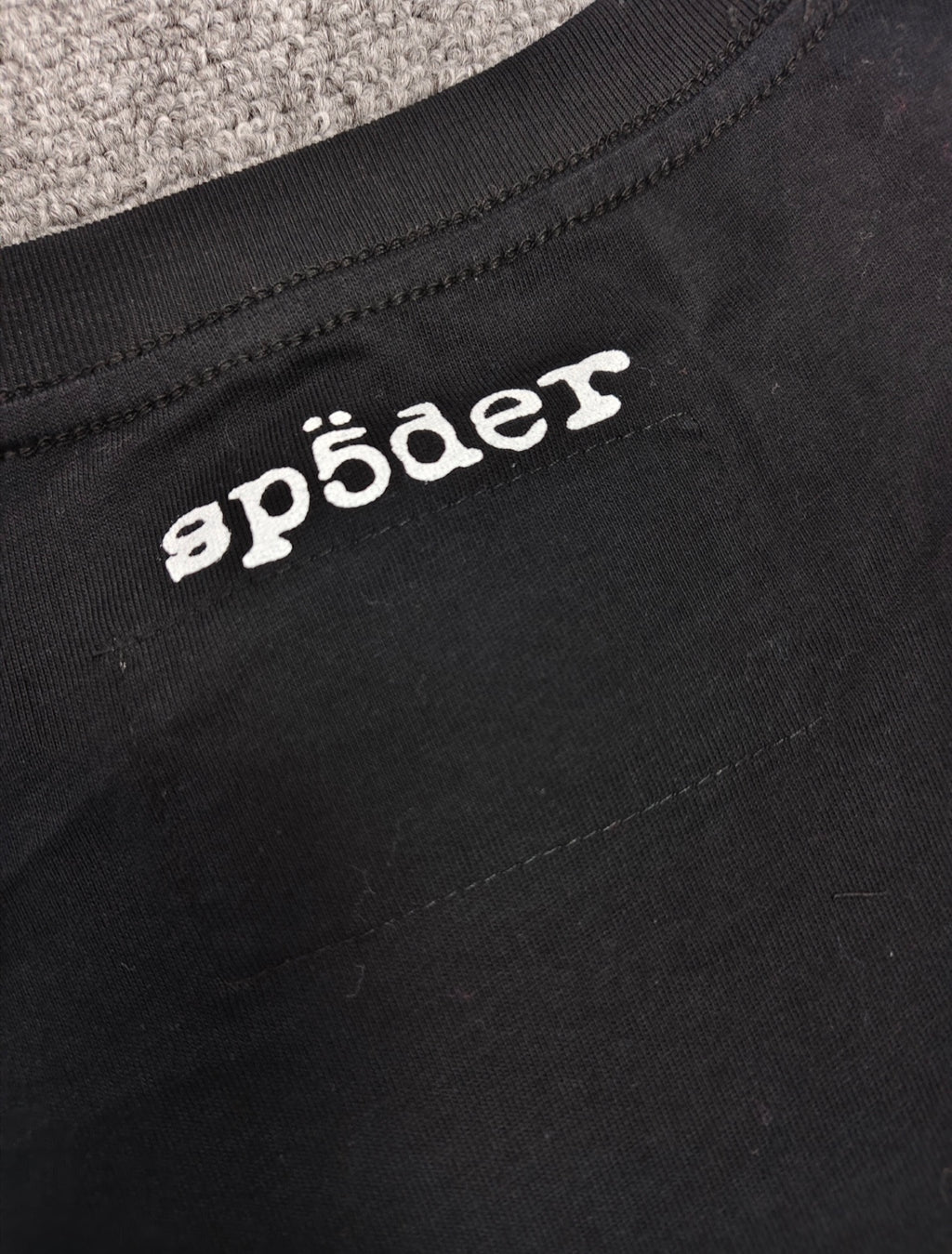 a black SP5DER Diffused Collegiate T-shirt featuring a large white, distressed graphic logo