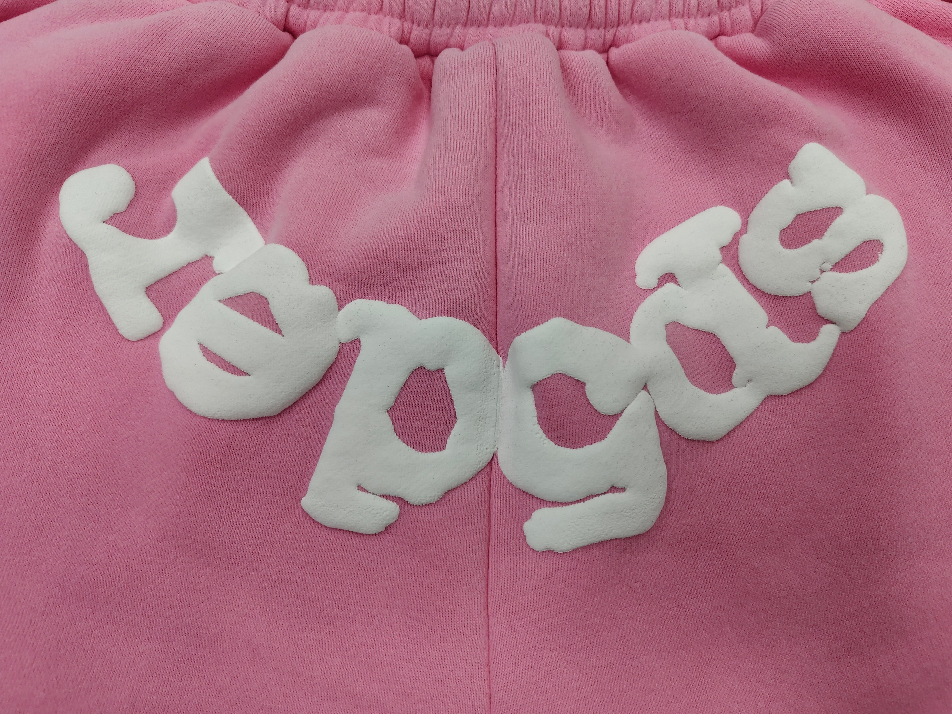 pink Sp5der jogger shorts feature a prominent white "sp5der" bubble letter graphic across the front
