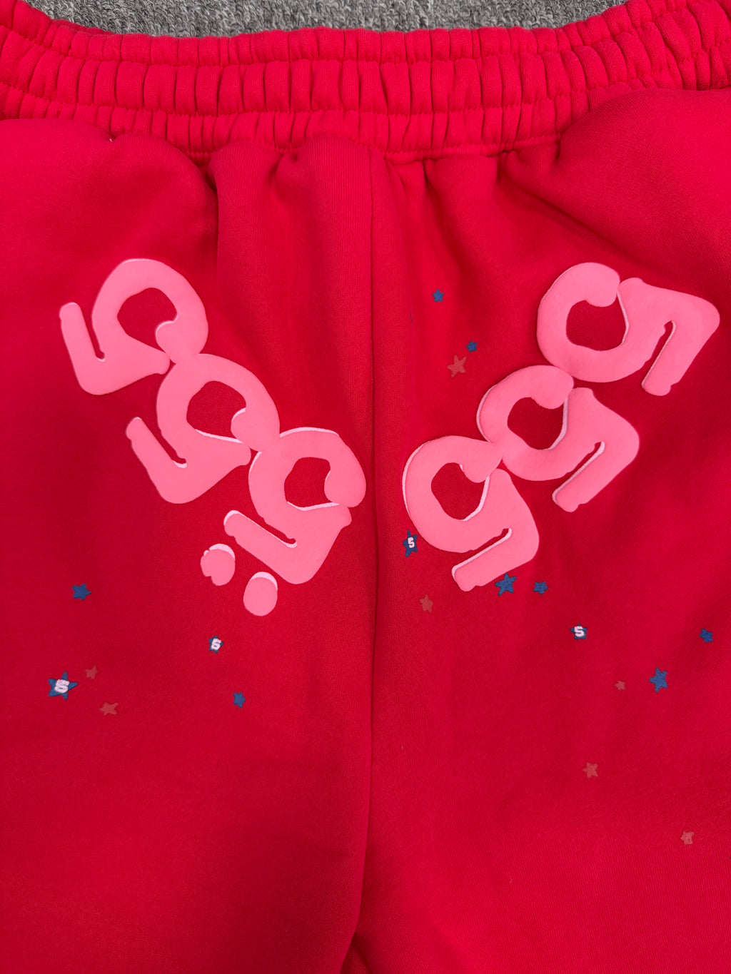 red Sp5der Angel Number Shorts featuring pink "555" graphics and star-shaped paint splatters