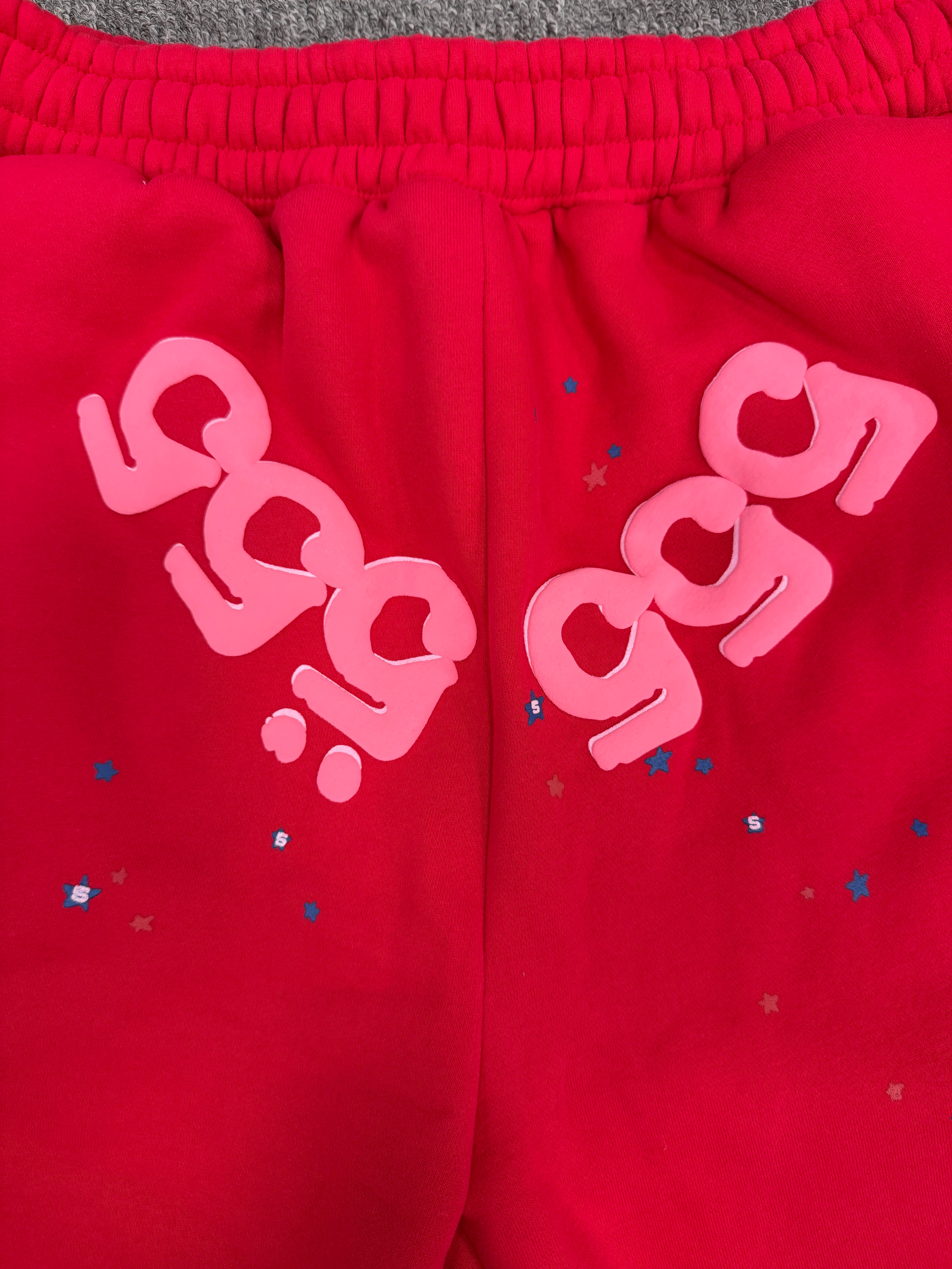 red Sp5der Angel Number Shorts featuring pink "555" graphics and star-shaped paint splatters