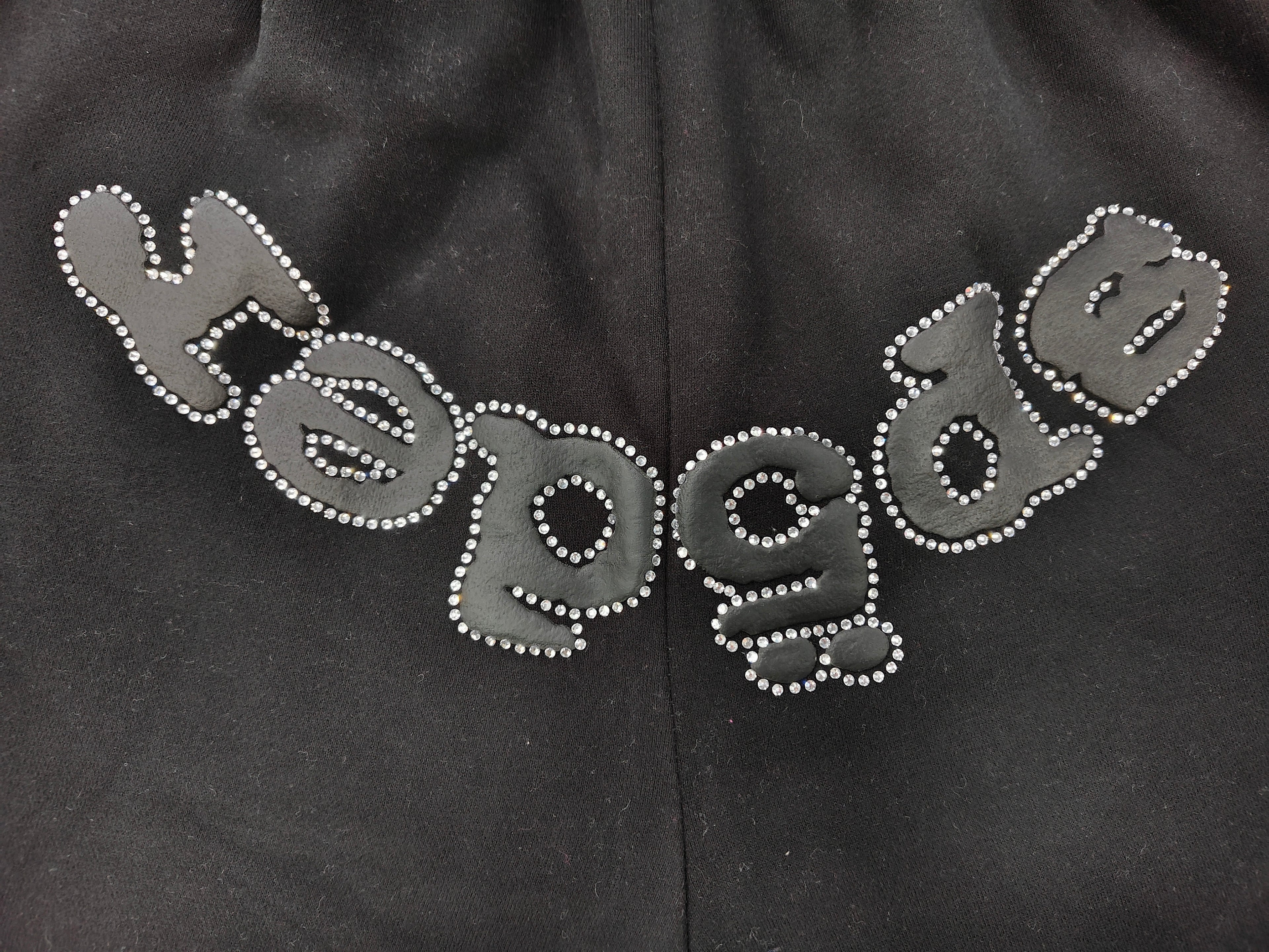 black Sp5der shorts feature a rhinestone-embellished logo and a spider web graphic