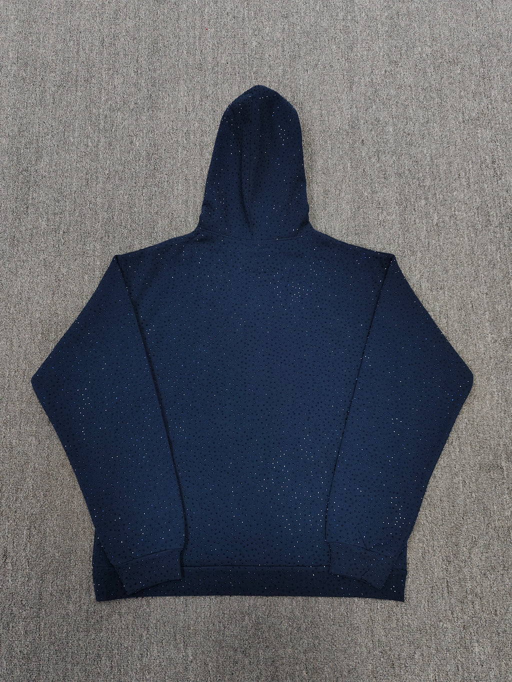 a Sp5der Worldwide navy blue hoodie featuring a pink rhinestone logo
