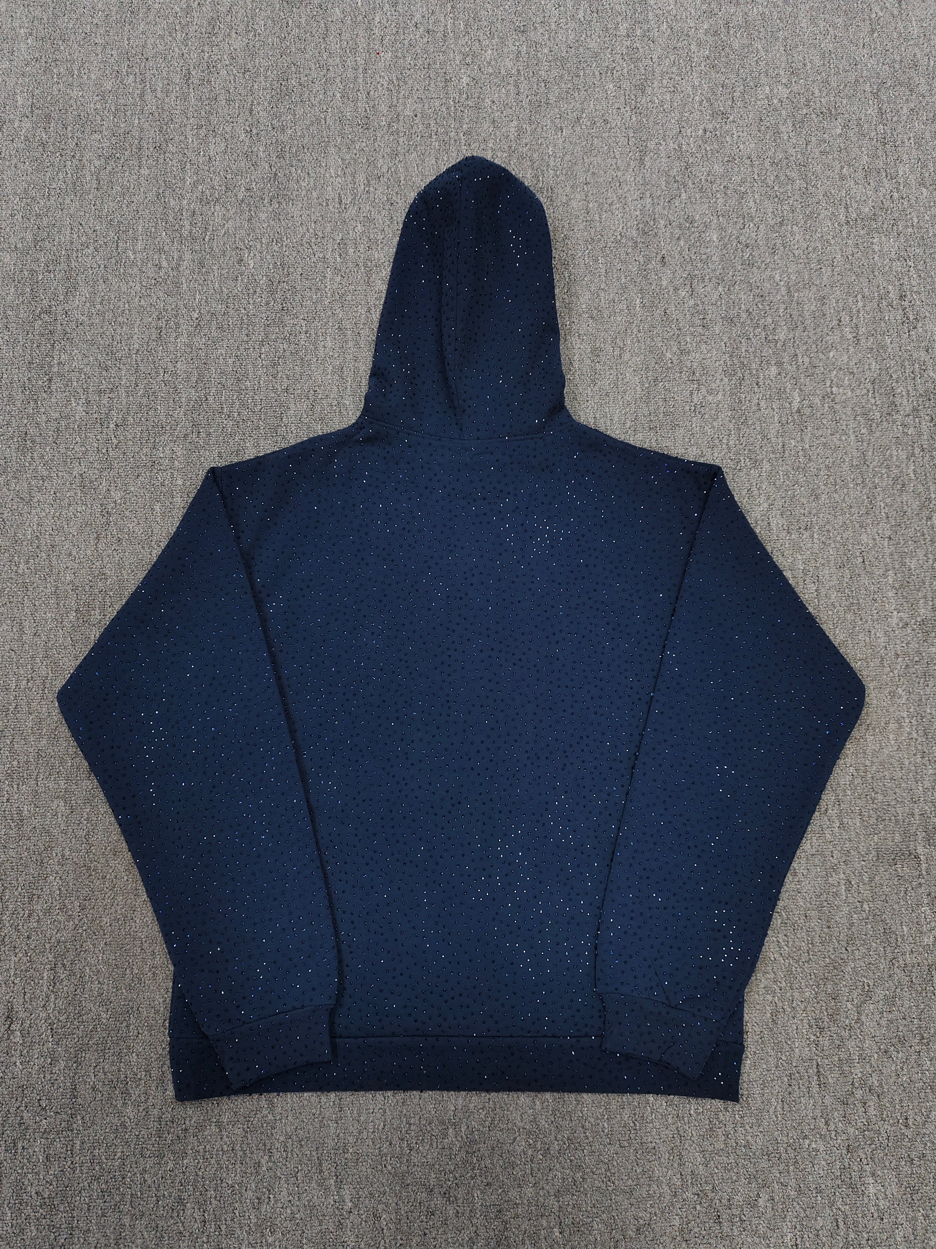 a Sp5der Worldwide navy blue hoodie featuring a pink rhinestone logo
