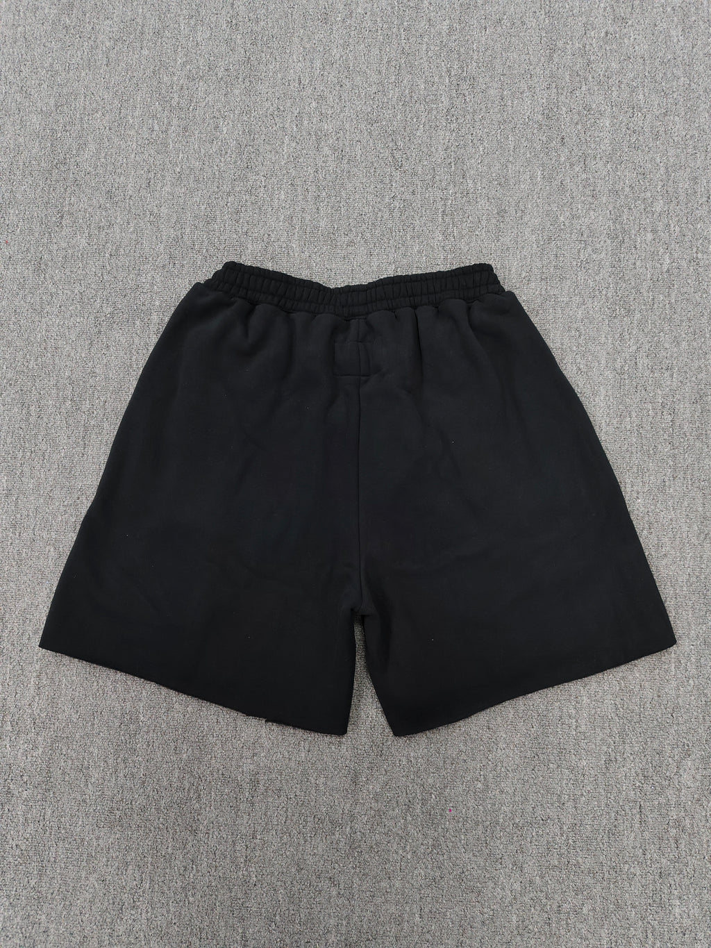 Sp5der x UY SCUTI collaboration shorts featuring bold red graphic logos on a black base