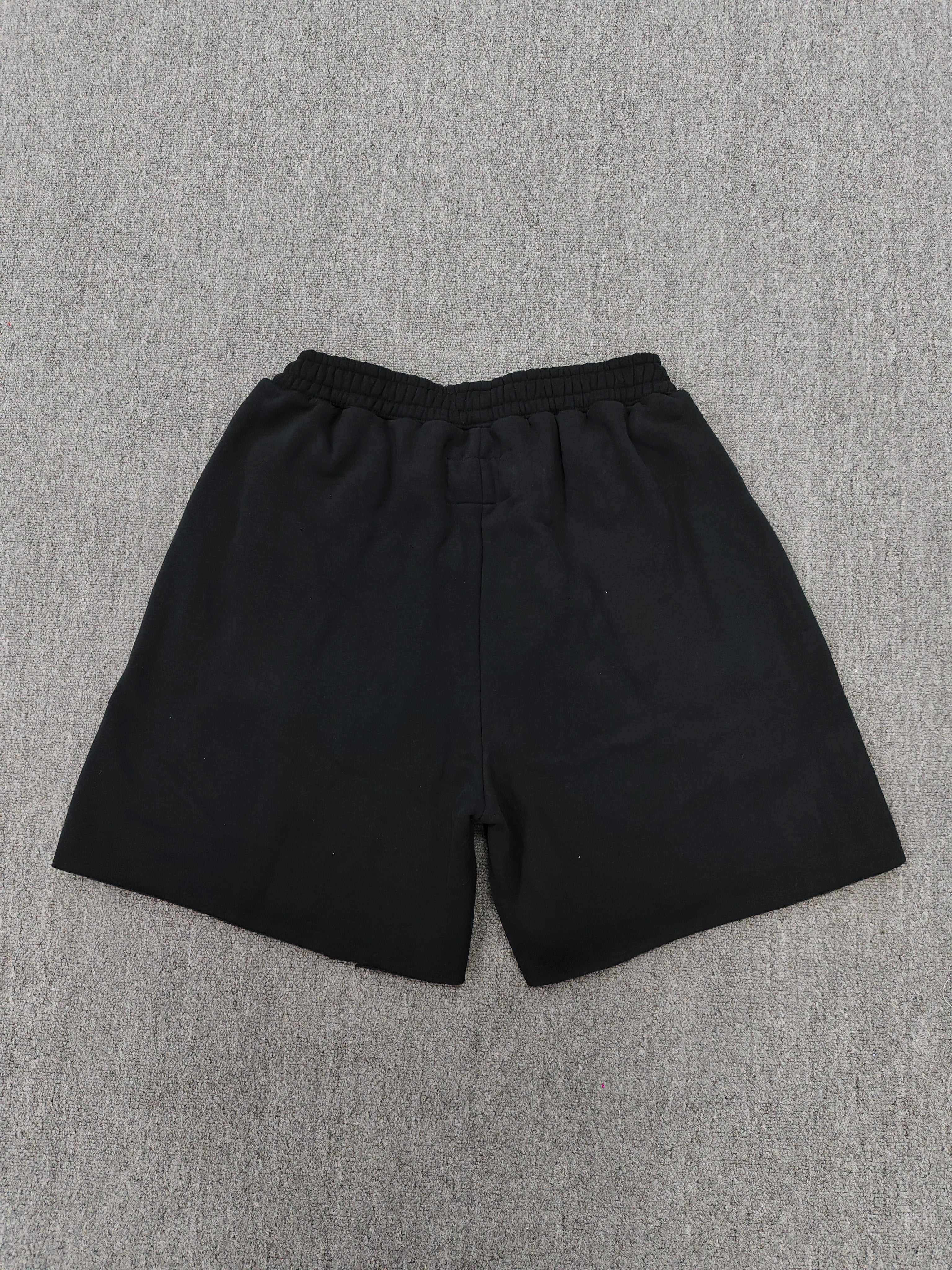 Sp5der x UY SCUTI collaboration shorts featuring bold red graphic logos on a black base