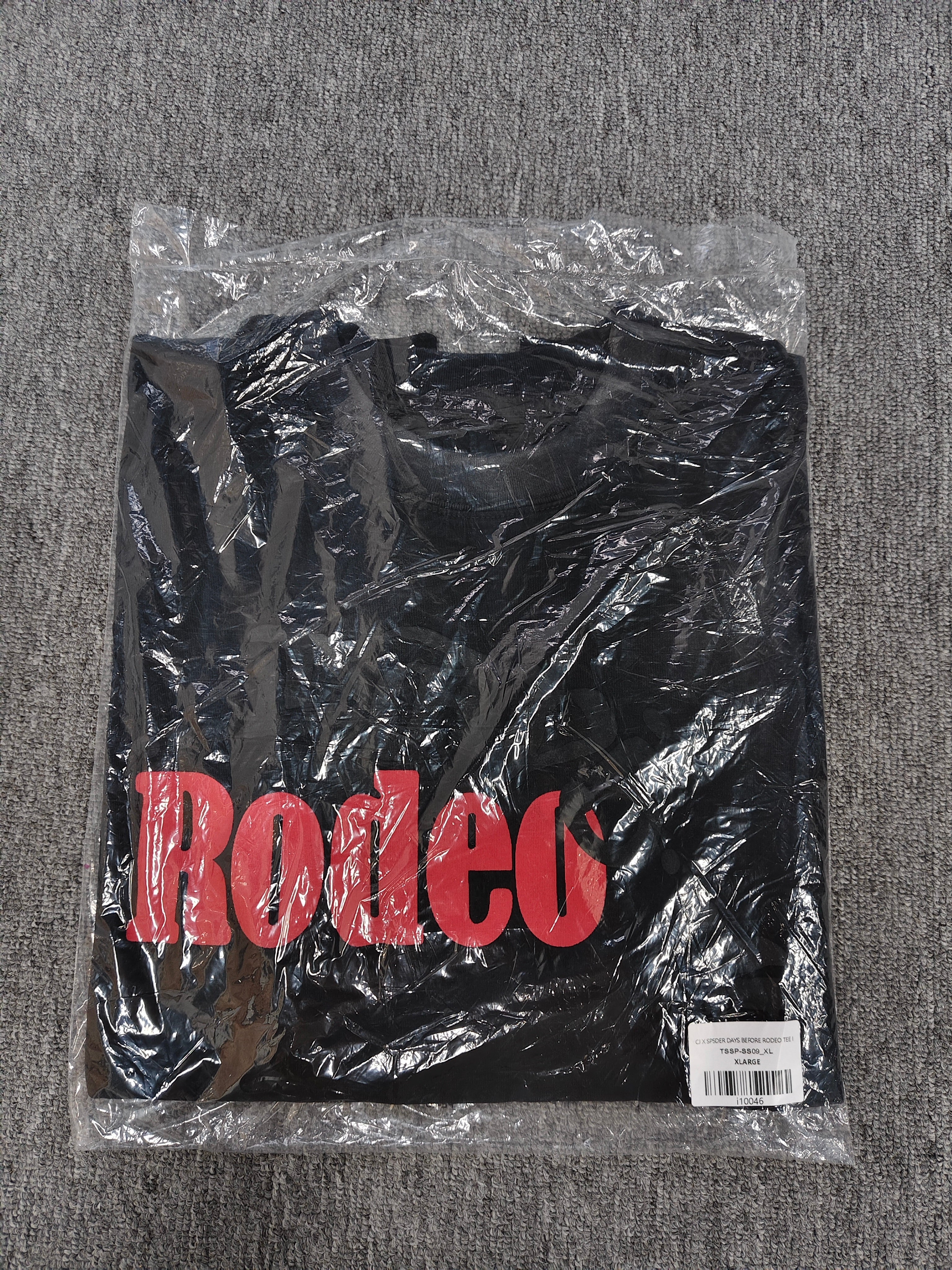 a black Travis Scott x Sp5der "Days Before Rodeo" collaboration t-shirt featuring a distinctive red "Rodeo" graphic and faded branding